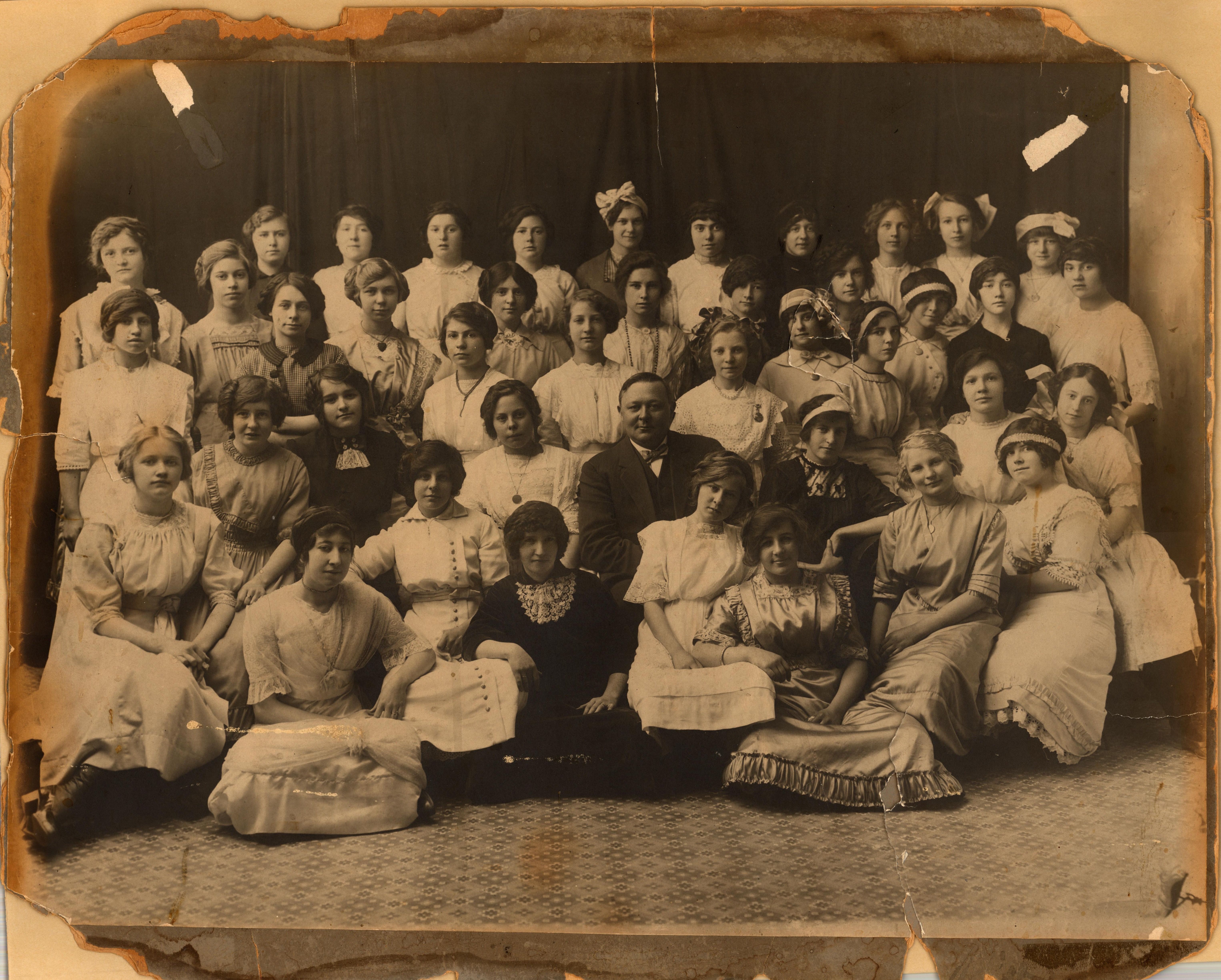 A 1918 photo of a high school girls choir with their instructor.