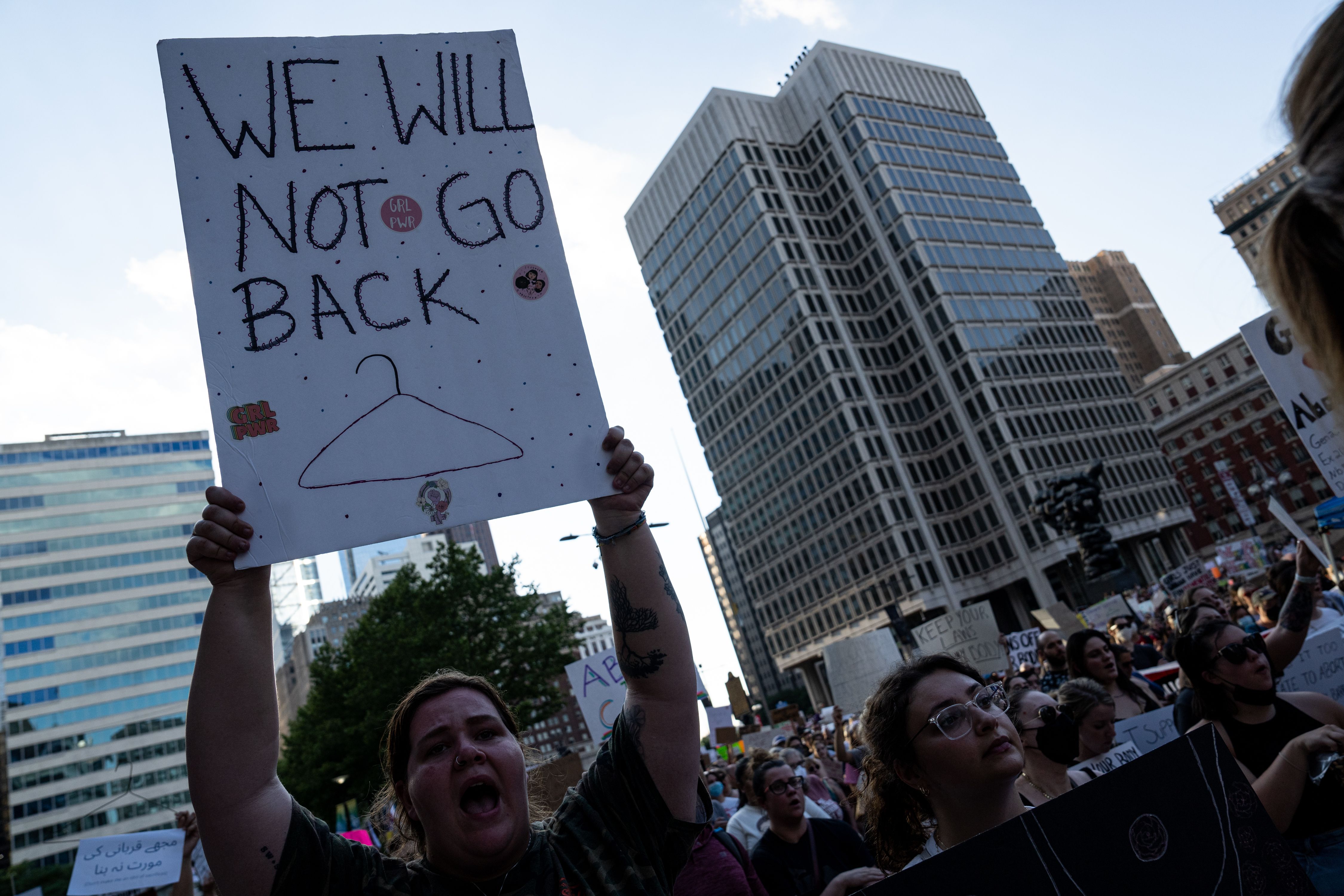 A photo of a woman holding up a sign that says "We will not go back" outside of Philadelphia City Hall.