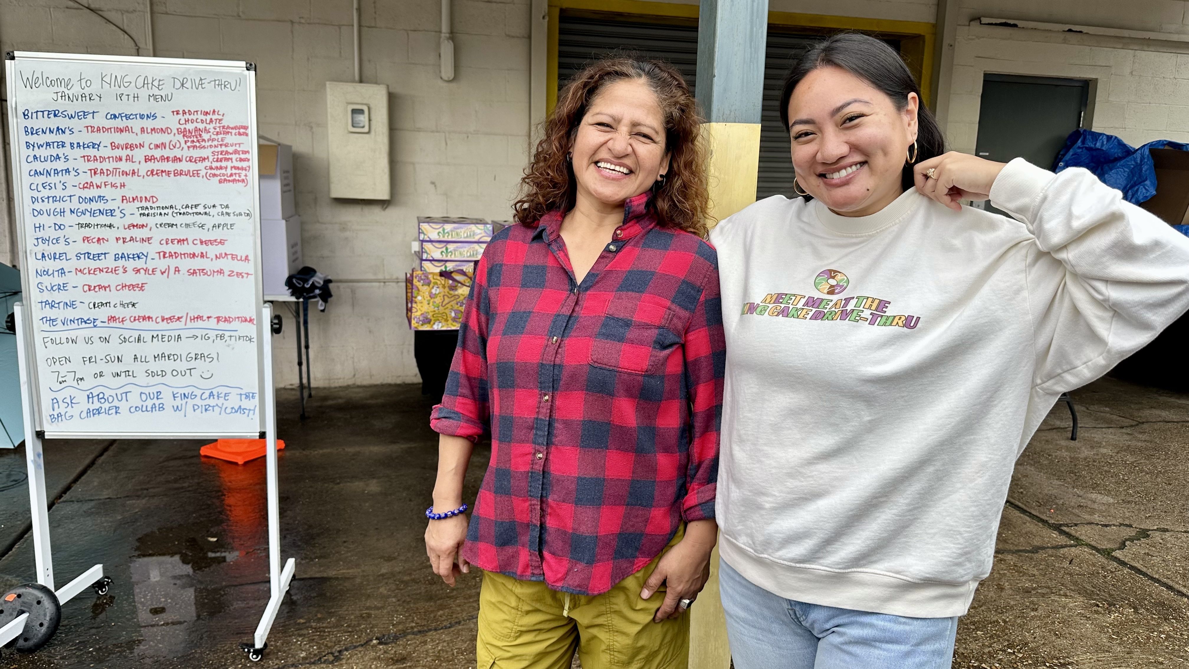 Photo shows two women smiling with a menu board.