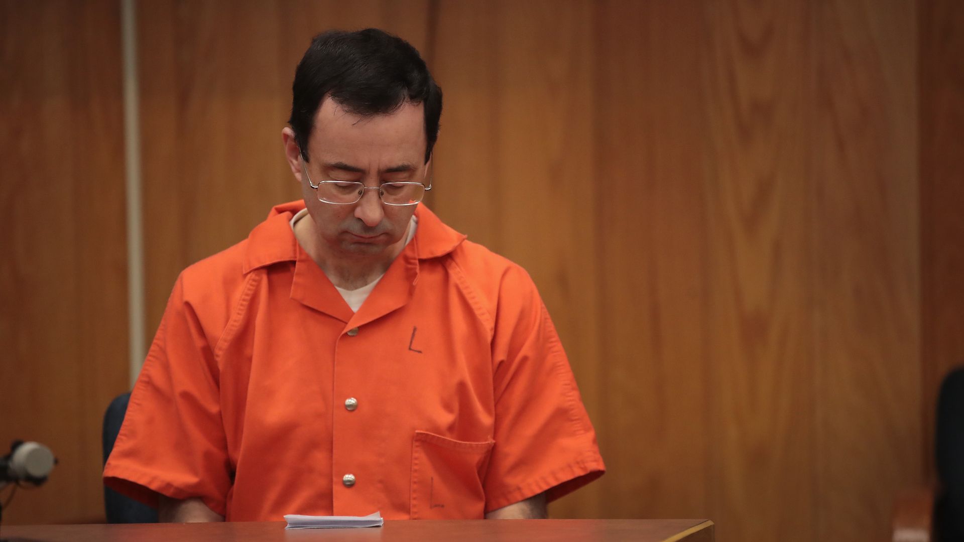 Larry Nassar, in an orange jumpsuit, looks down during his sentencing