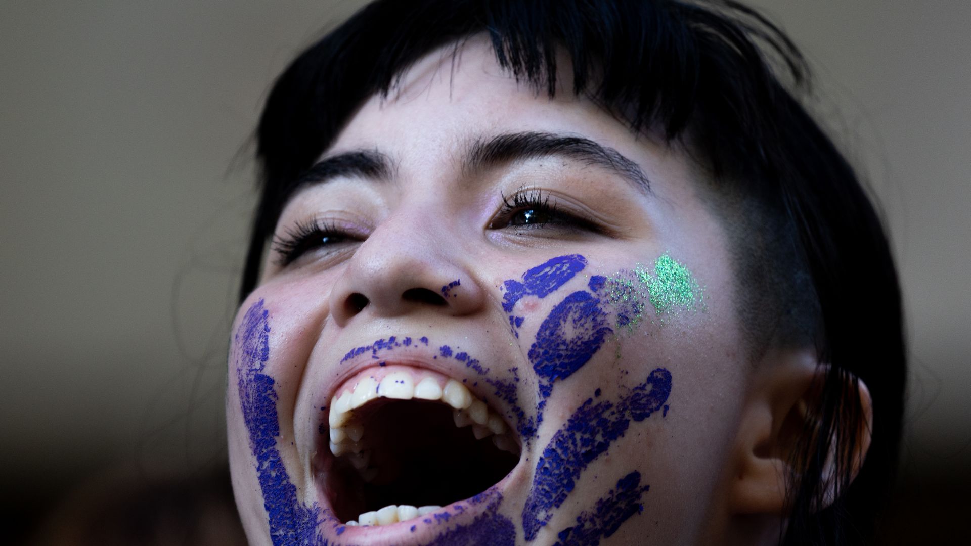 a woman with a blue handprint on her face smiles wide