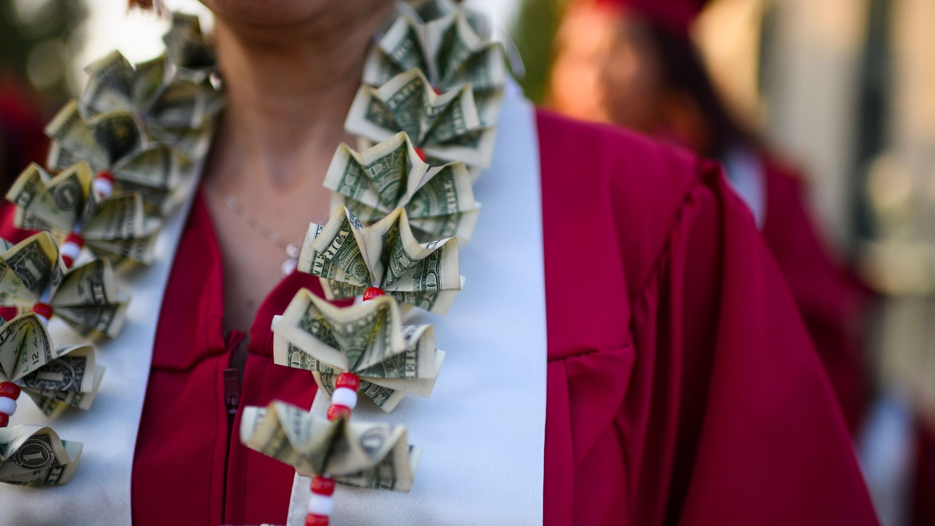 In this image, a woman wears a gown with a sash and folded dollar bills.