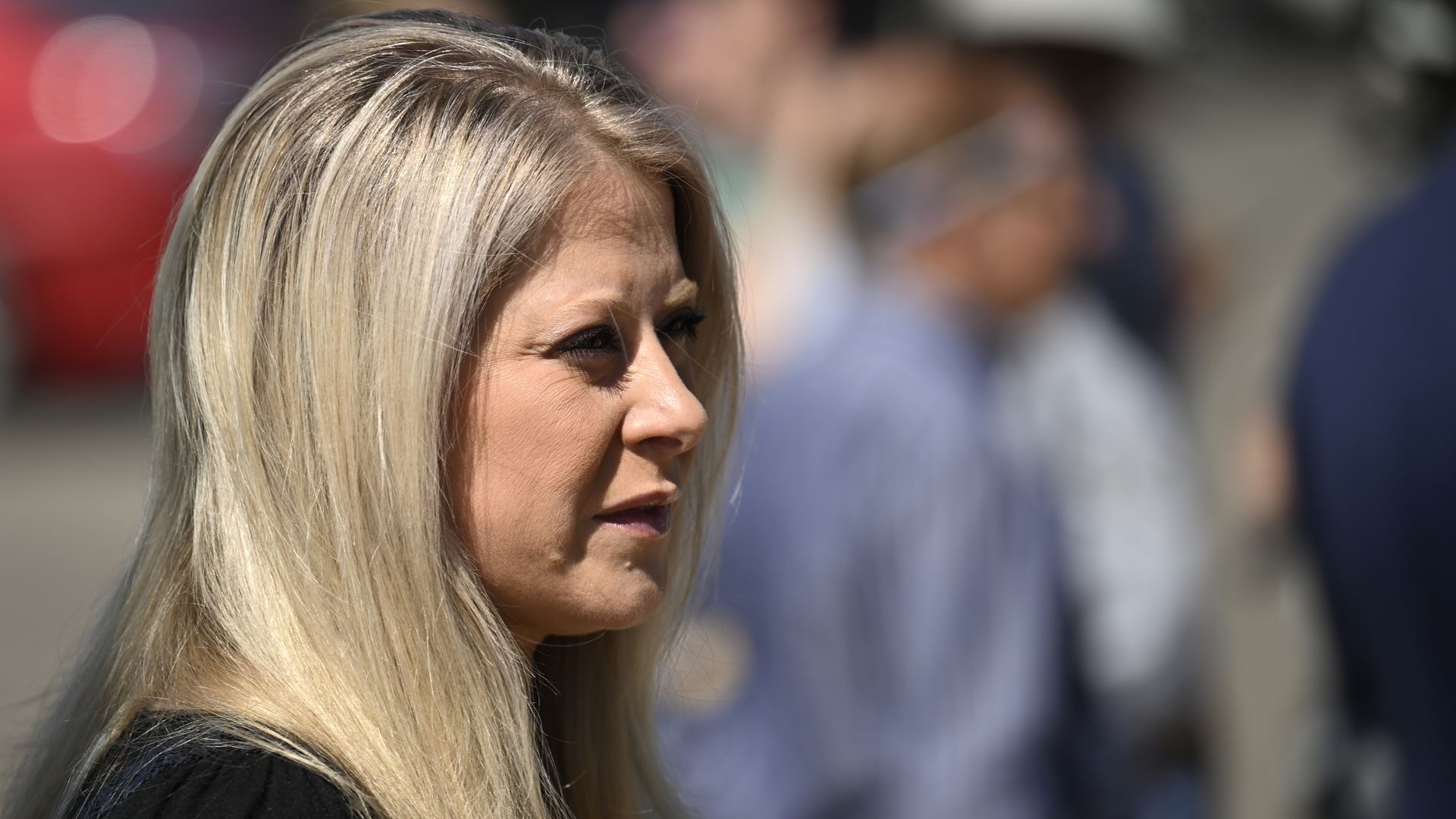 A woman with blonde hair looks on. 