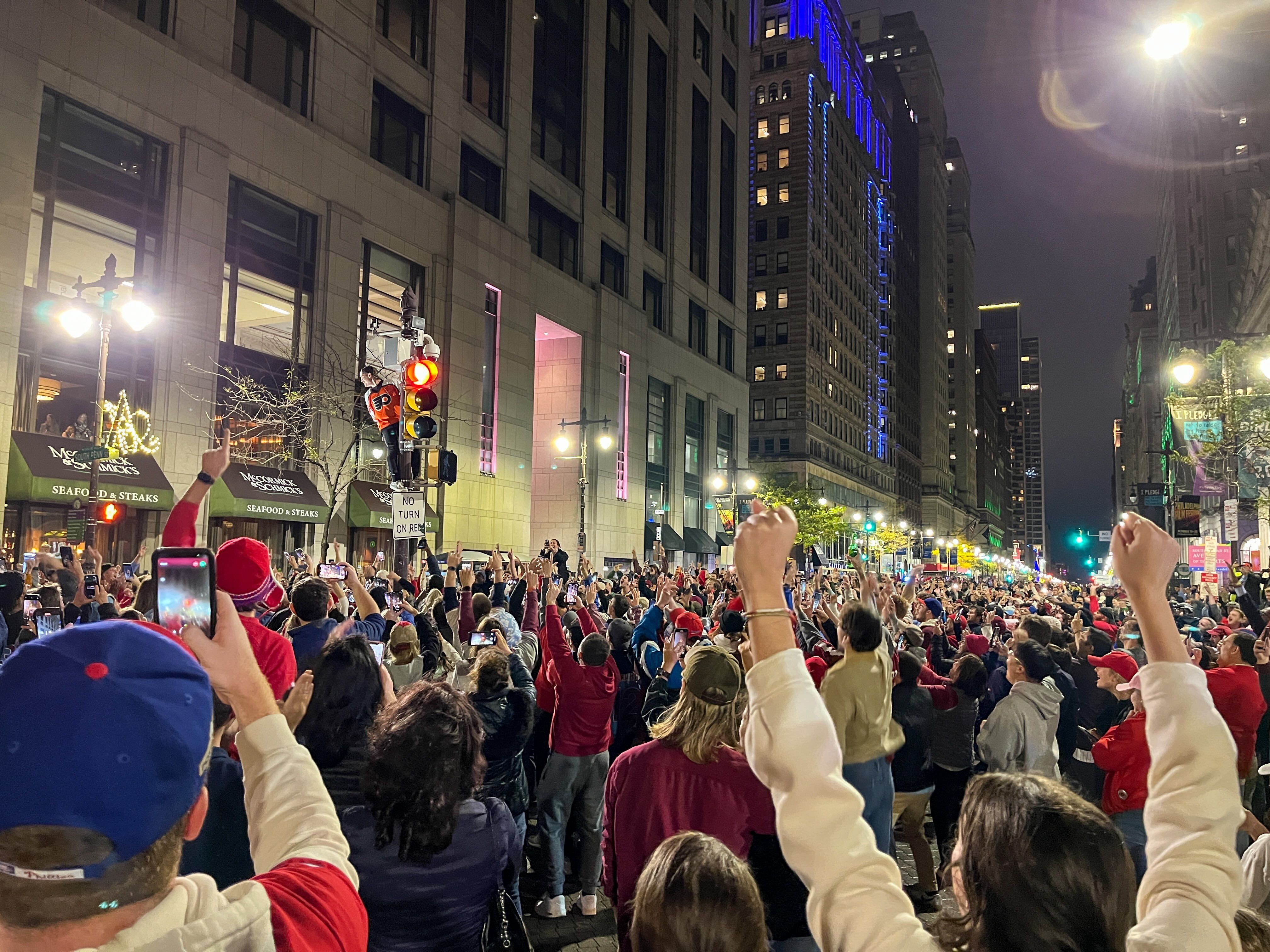 Phillies fans climb a traffic light in downtown Philadelphia after the game Sunday.
