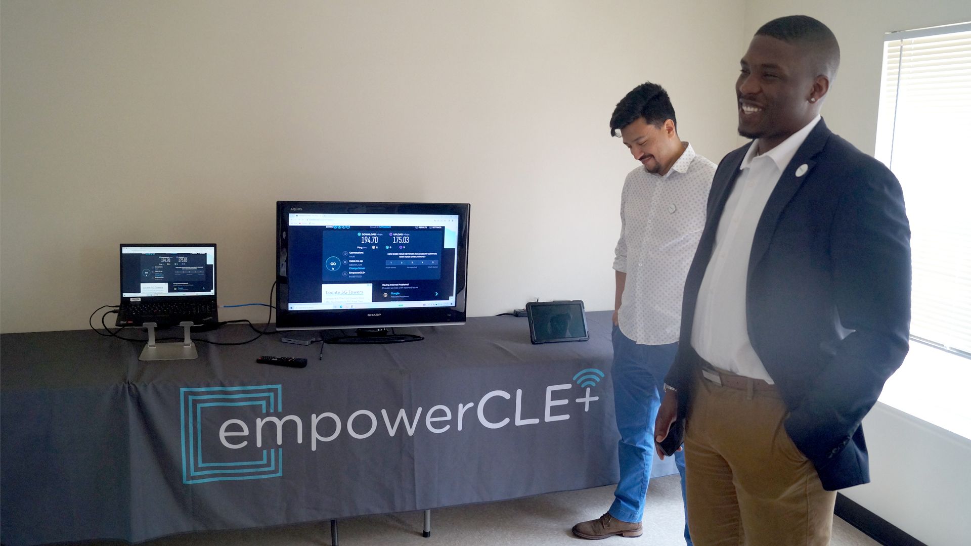 DigitalC CEO Joshua Edmonds (R) and director of technology Rolando Alvarez in a room with a monitor showing internet download speeds.