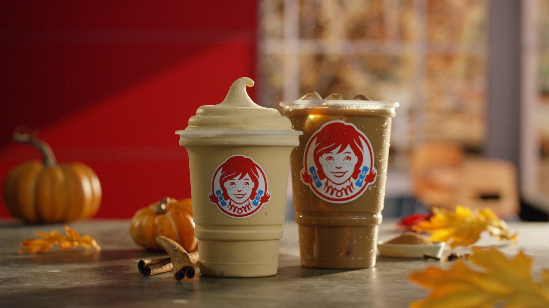 Two fall-themed frostys on a table with pumpkin and leaf decorations.