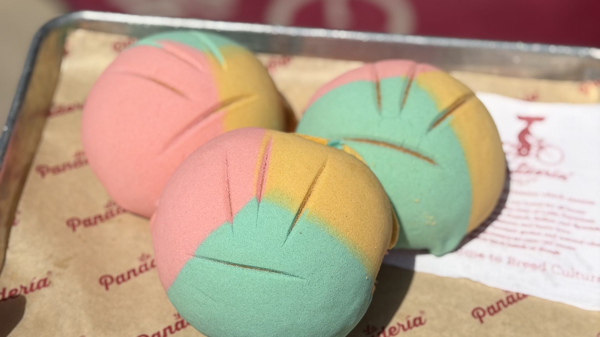 Three Fiesta-themed mini conchas from San Antonio's La Panadería are shown with pastel pink, yellow and green colors.