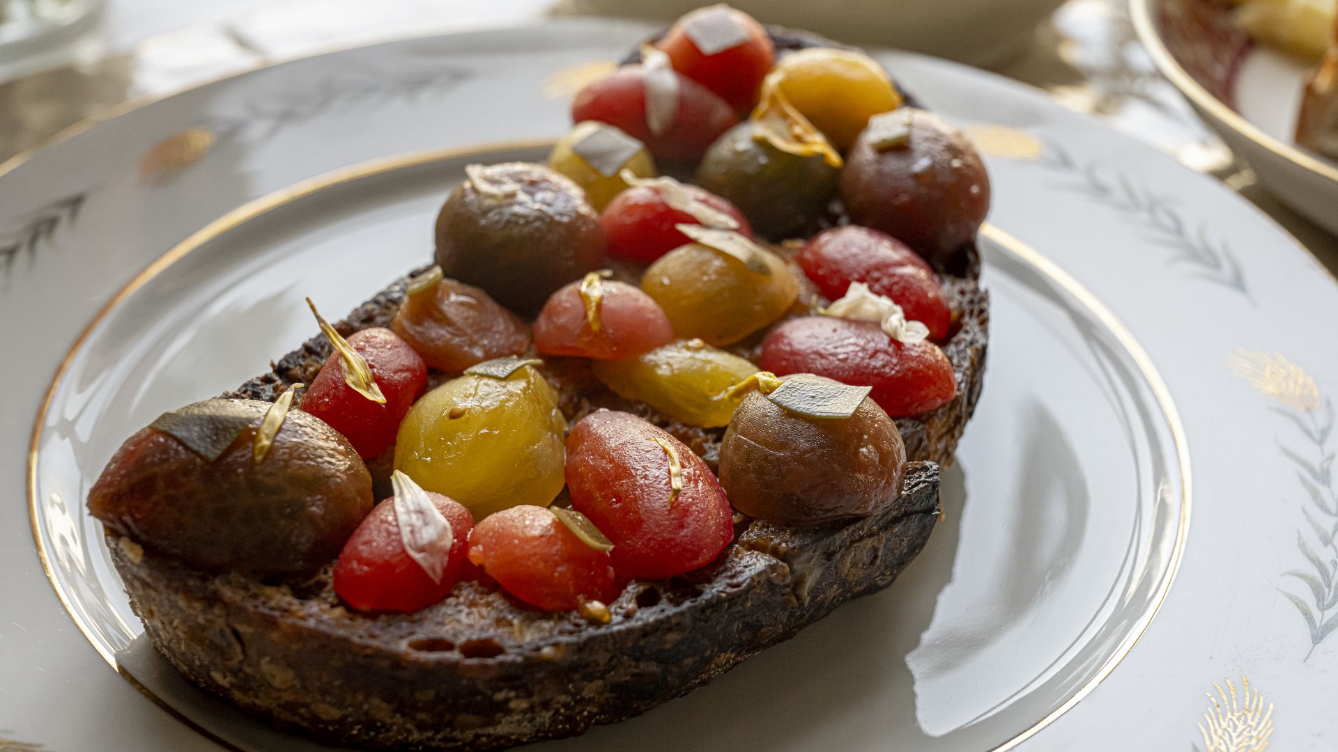 A pile of heirloom cherry tomatoes on a toasted slice of sourdough.