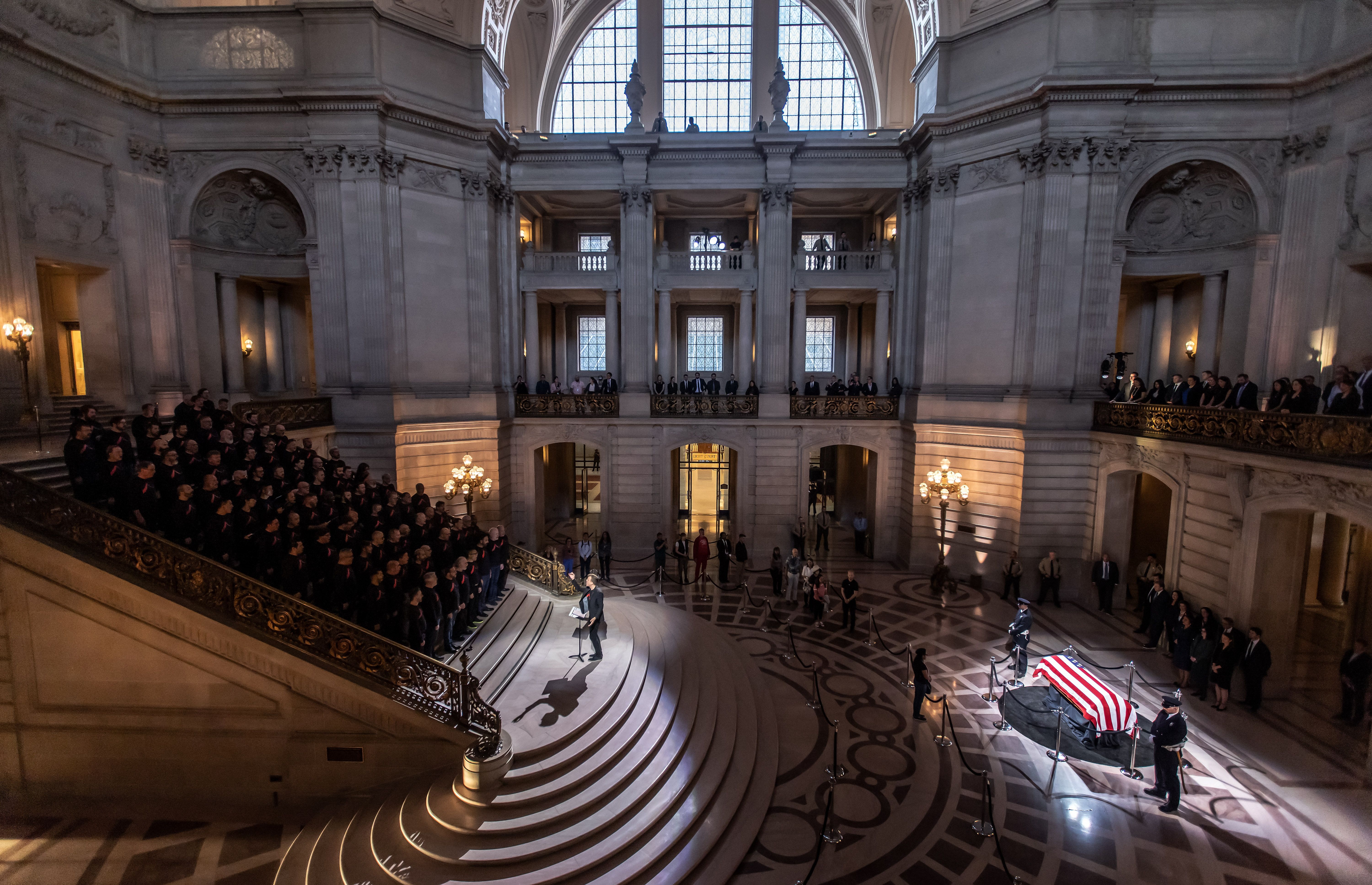 Choir stands on left on stairs with Pelosi's casket on the right 