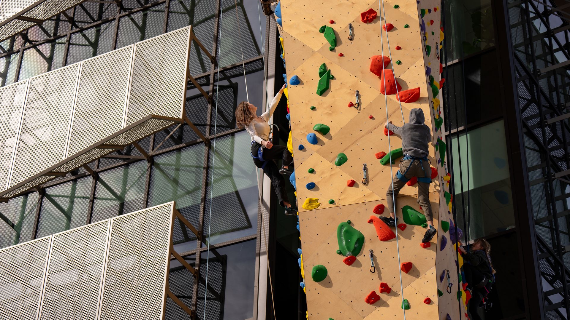 Two climbers climb a wall at Millcreek City Hall.