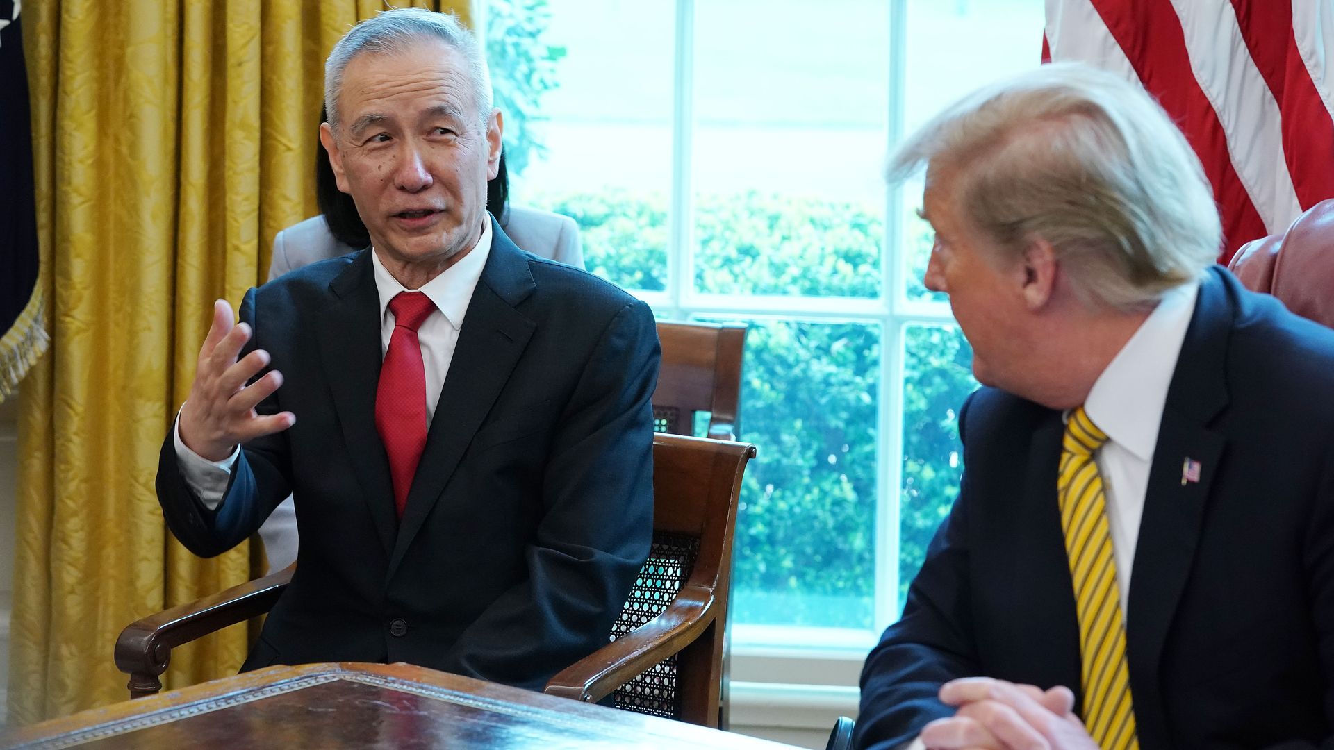 In this image, Trump sits at his desk in the Oval Office and listens to Liu He.