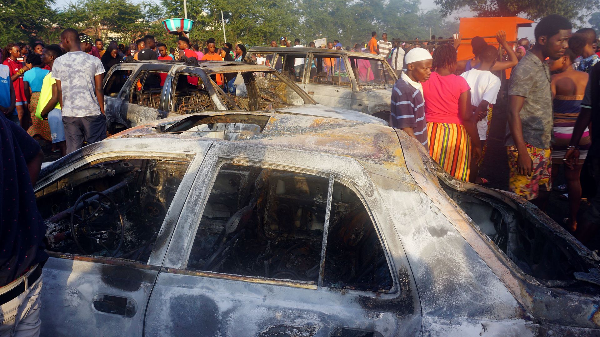 People look on at burnt cars in the aftermath of a fuel tanker explosion in Freetown on November 6,