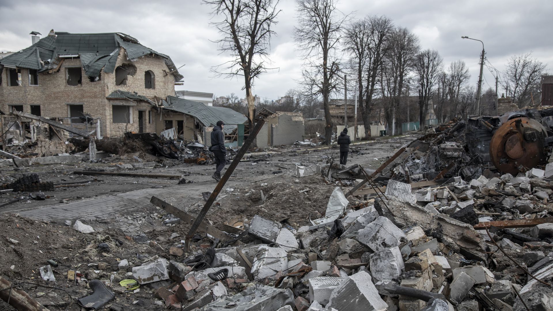 Civilians walk amid the destruction on a street in the town of Bucha, 