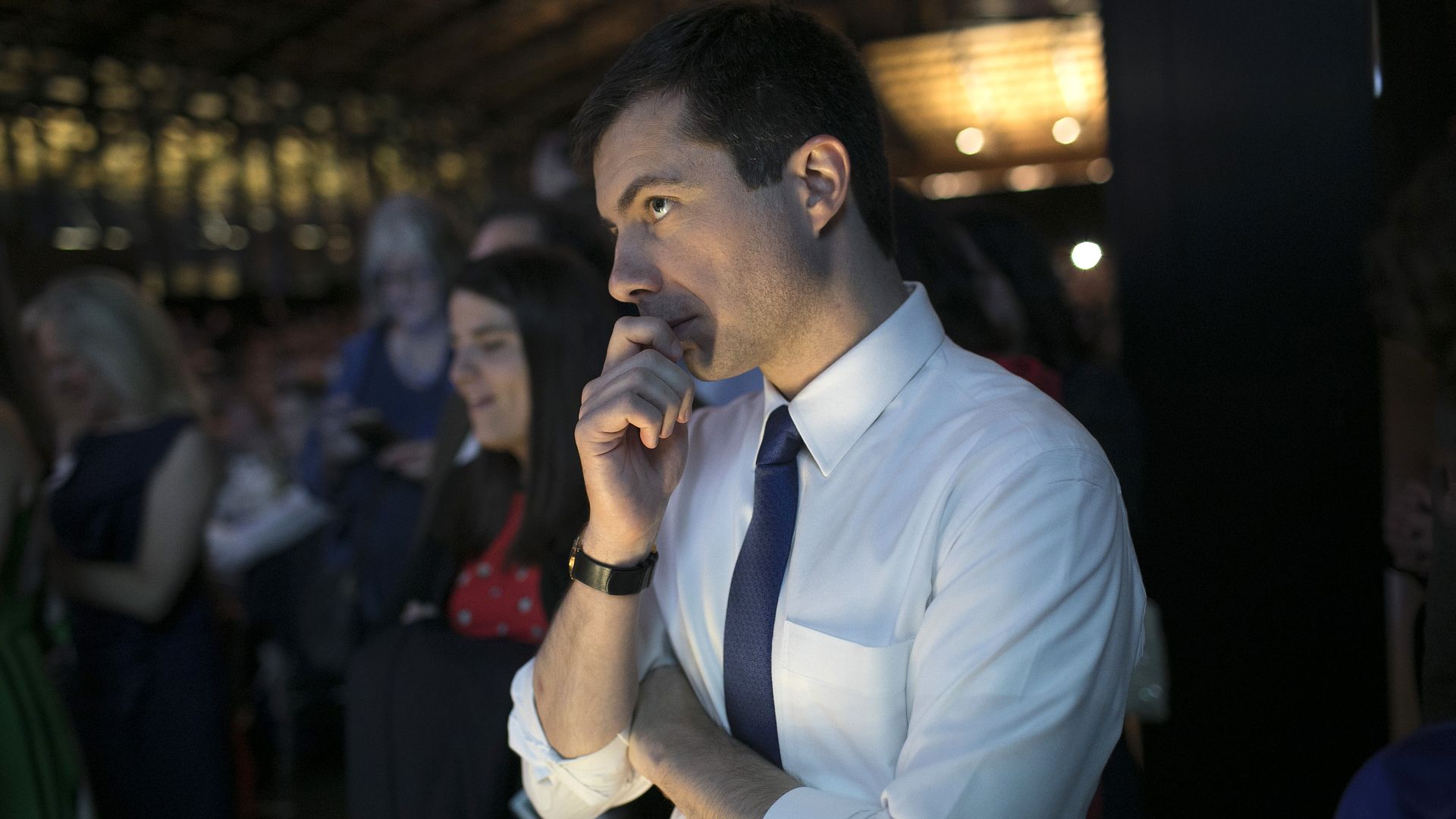 Pete Buttigieg standing with his hand over his mouth. 