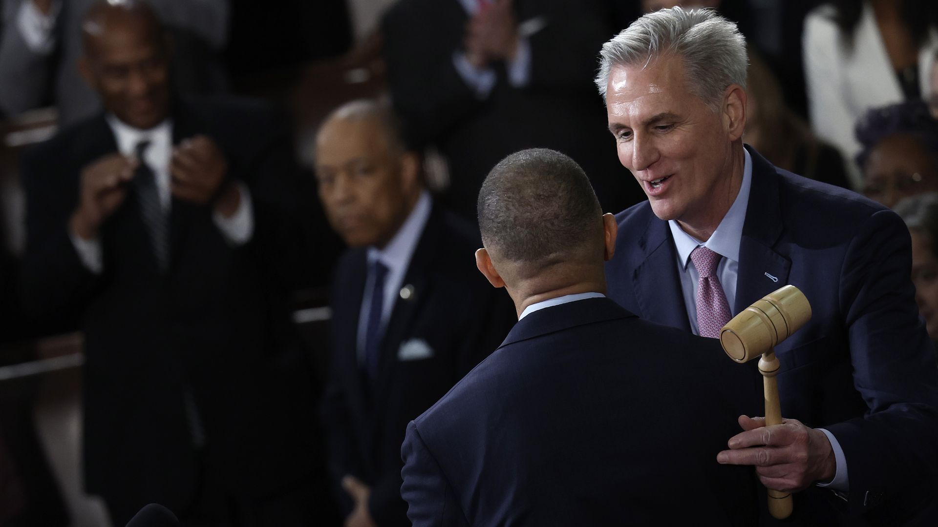 House Speaker Kevin McCarthy holds a gavel while speaking to Minority Leader Hakeem Jeffries at the House rostrum. Both are wearing blue suits.