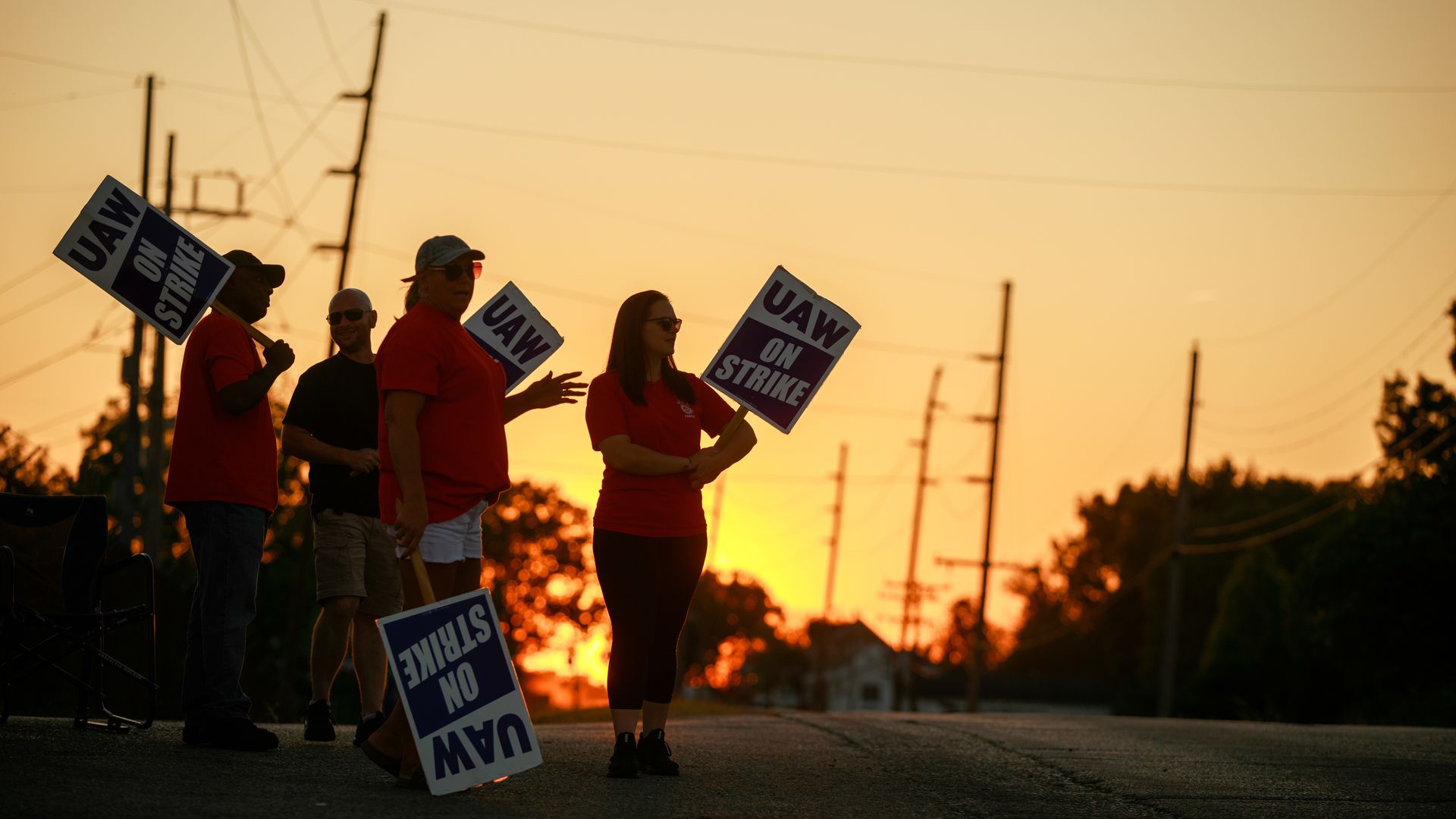 People holding picket signs as the sun sets