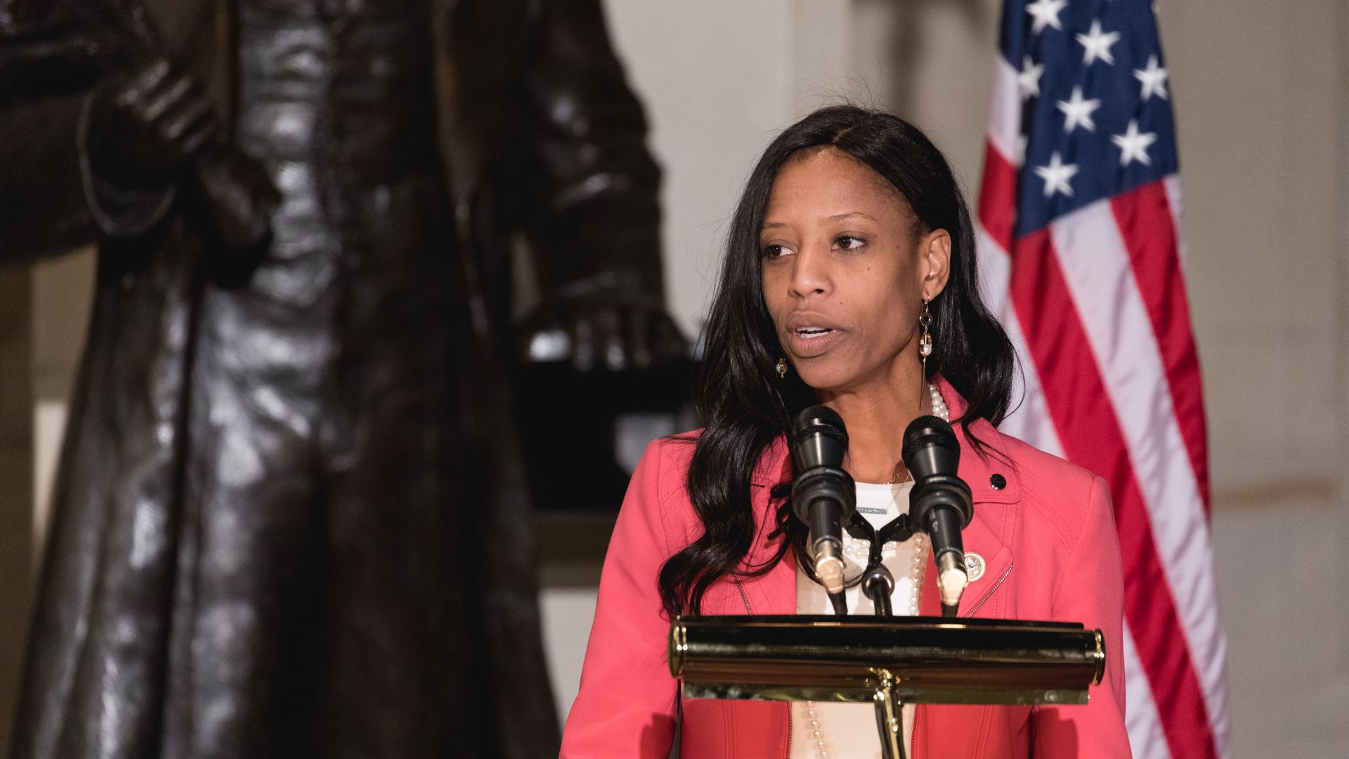 Mia Love before an American flag at a podium speaks.