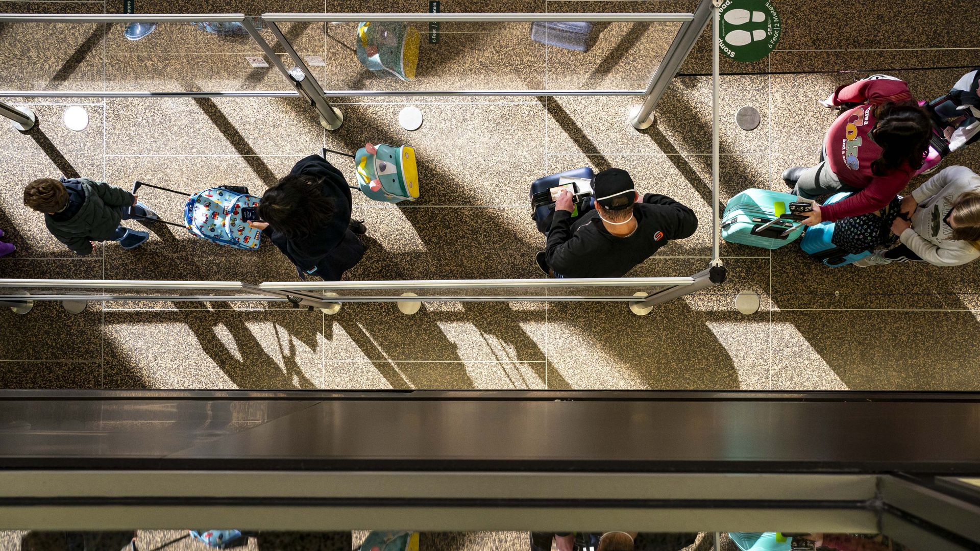 A bird's eye view of travelers waiting in line at Seattle-Tacoma International Airport. 