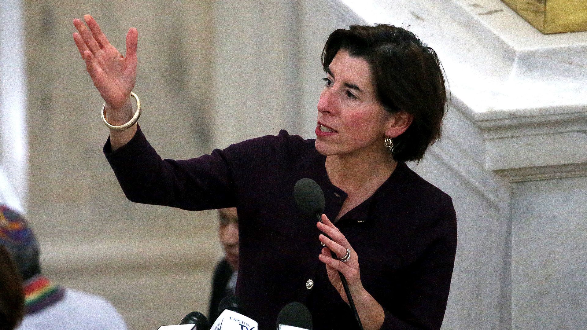 Picture of Gina Raimondo speaking behind a line of microphones