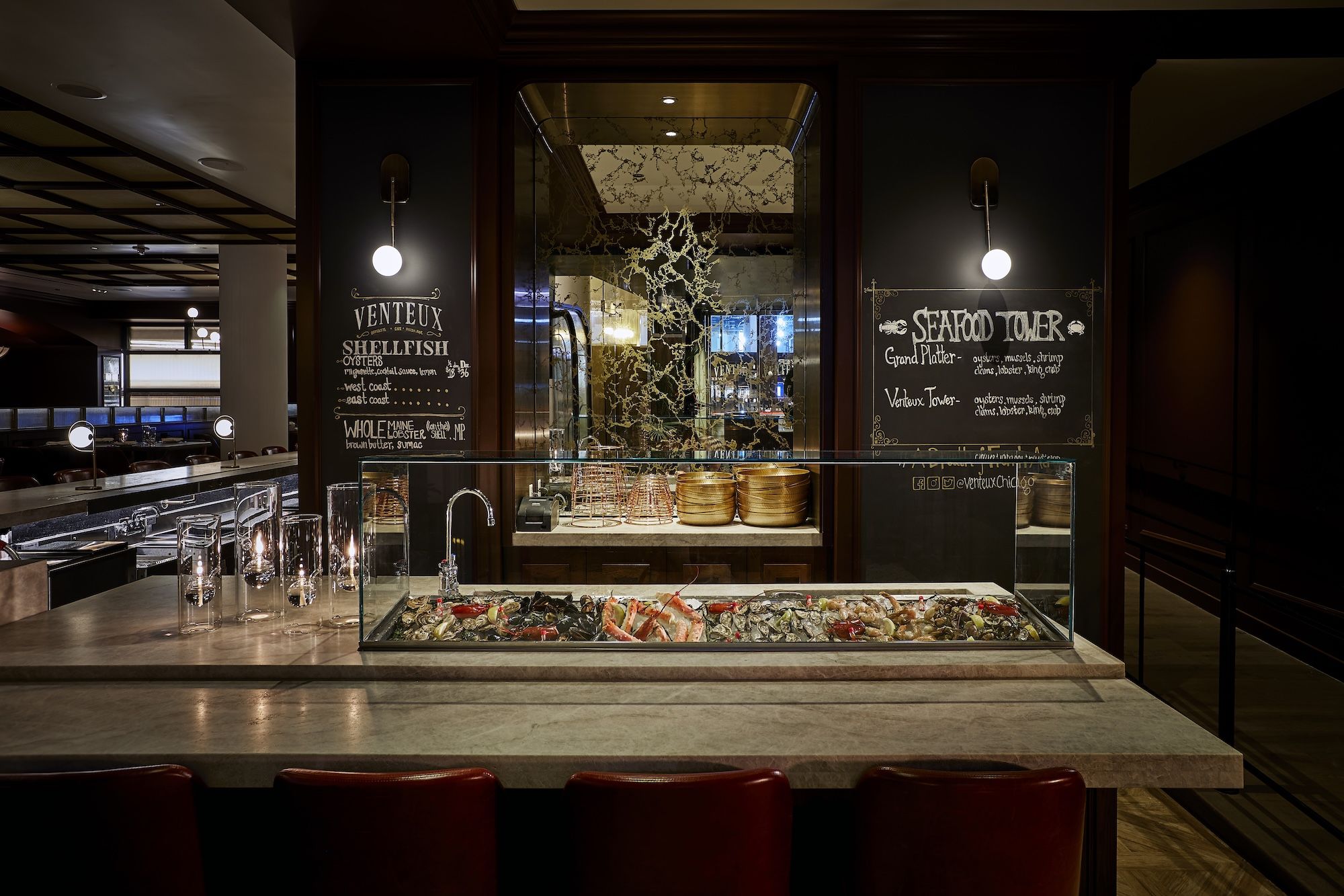 An oyster bar at a restaurant with a chalkboard on the walls behind it.