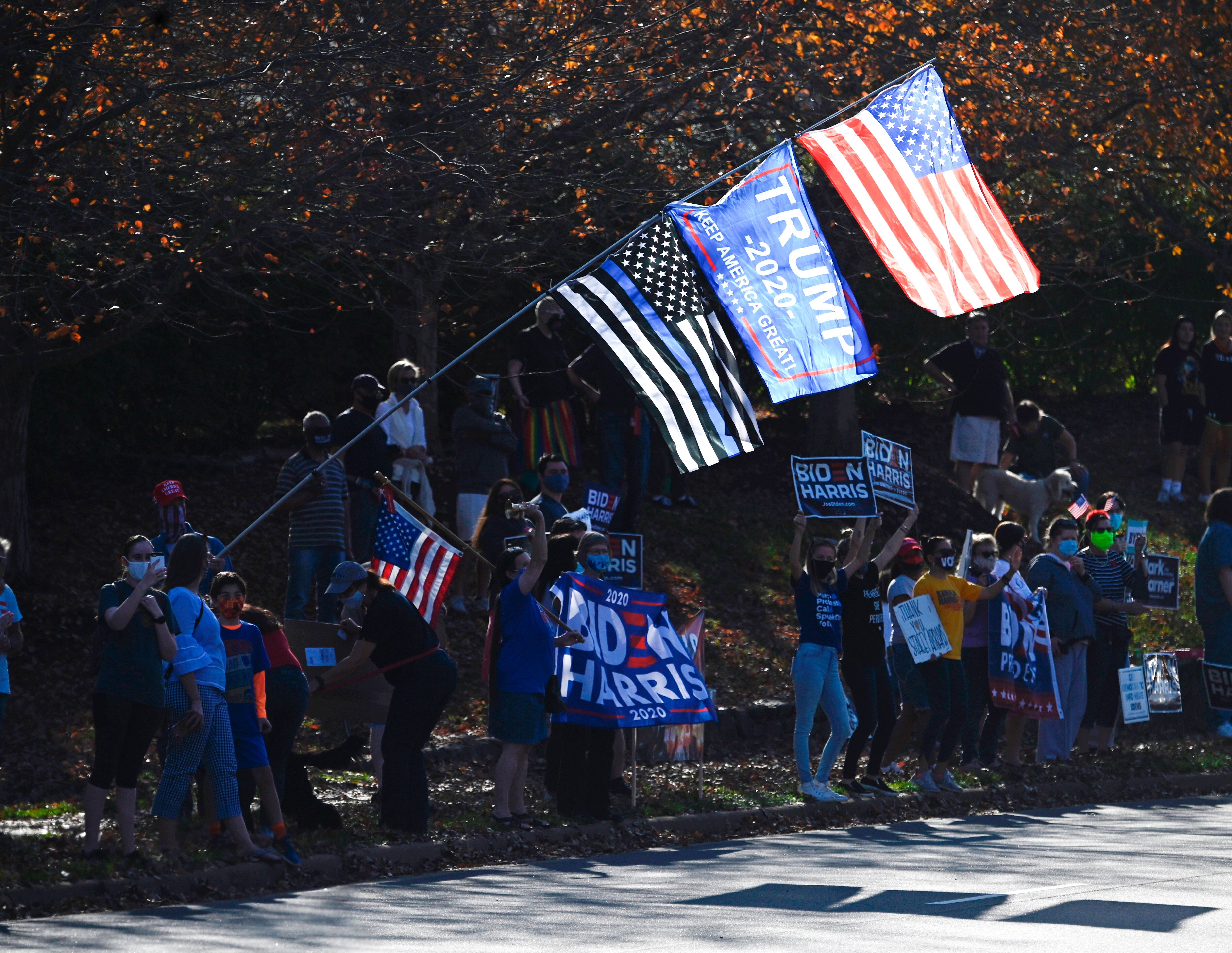 A Trump supporter waves flags as people celebrate the election of president-elect Joe Biden at the International golf club in Sterling, Virginia 