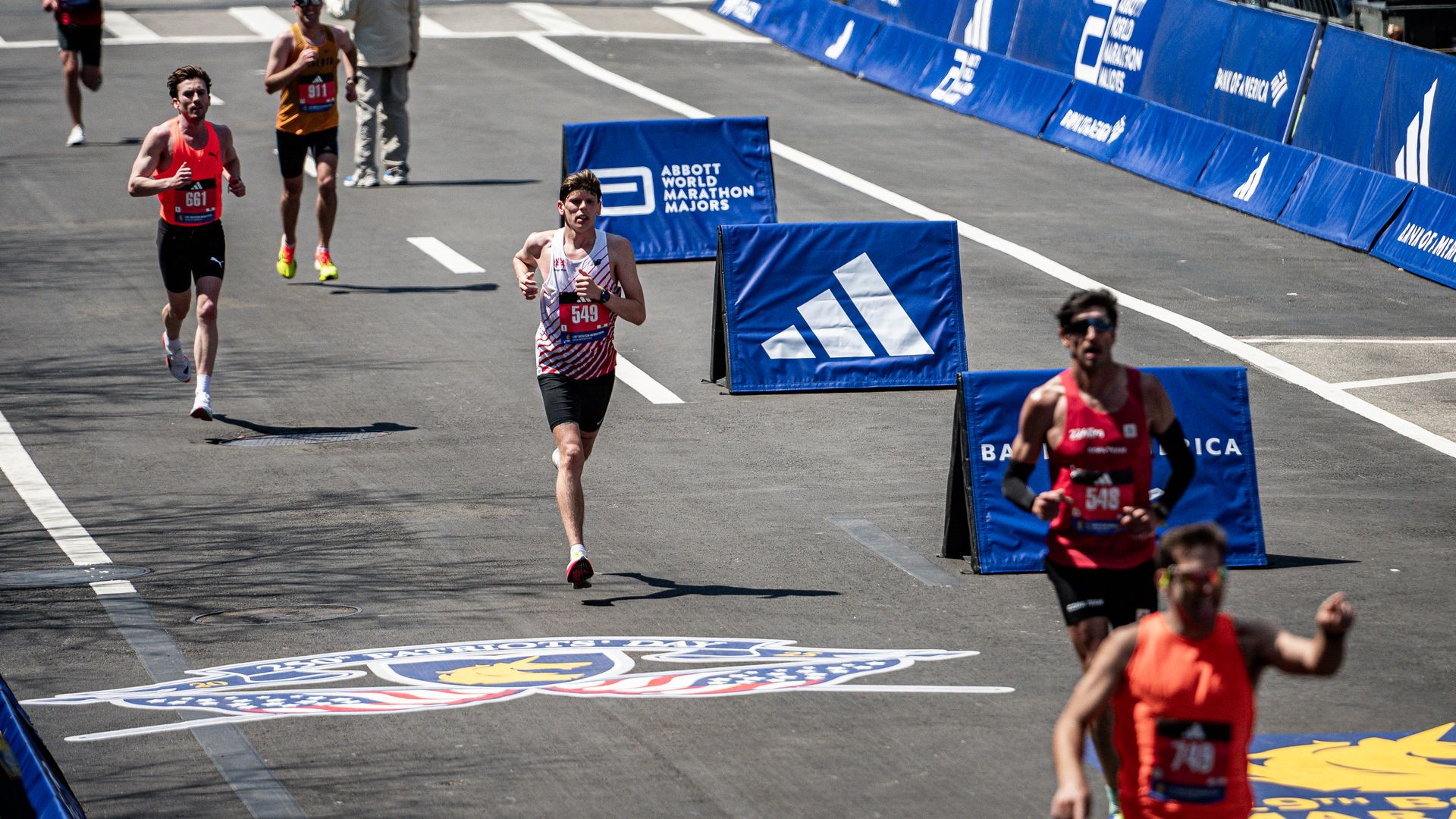 Several athletes running along the Boston Marathon route in 2025.
