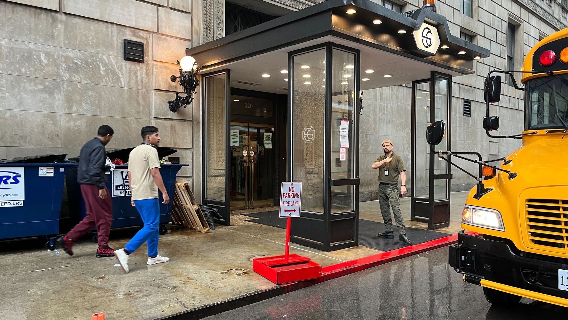 Photo of the front of a hotel with a bus parked out front 