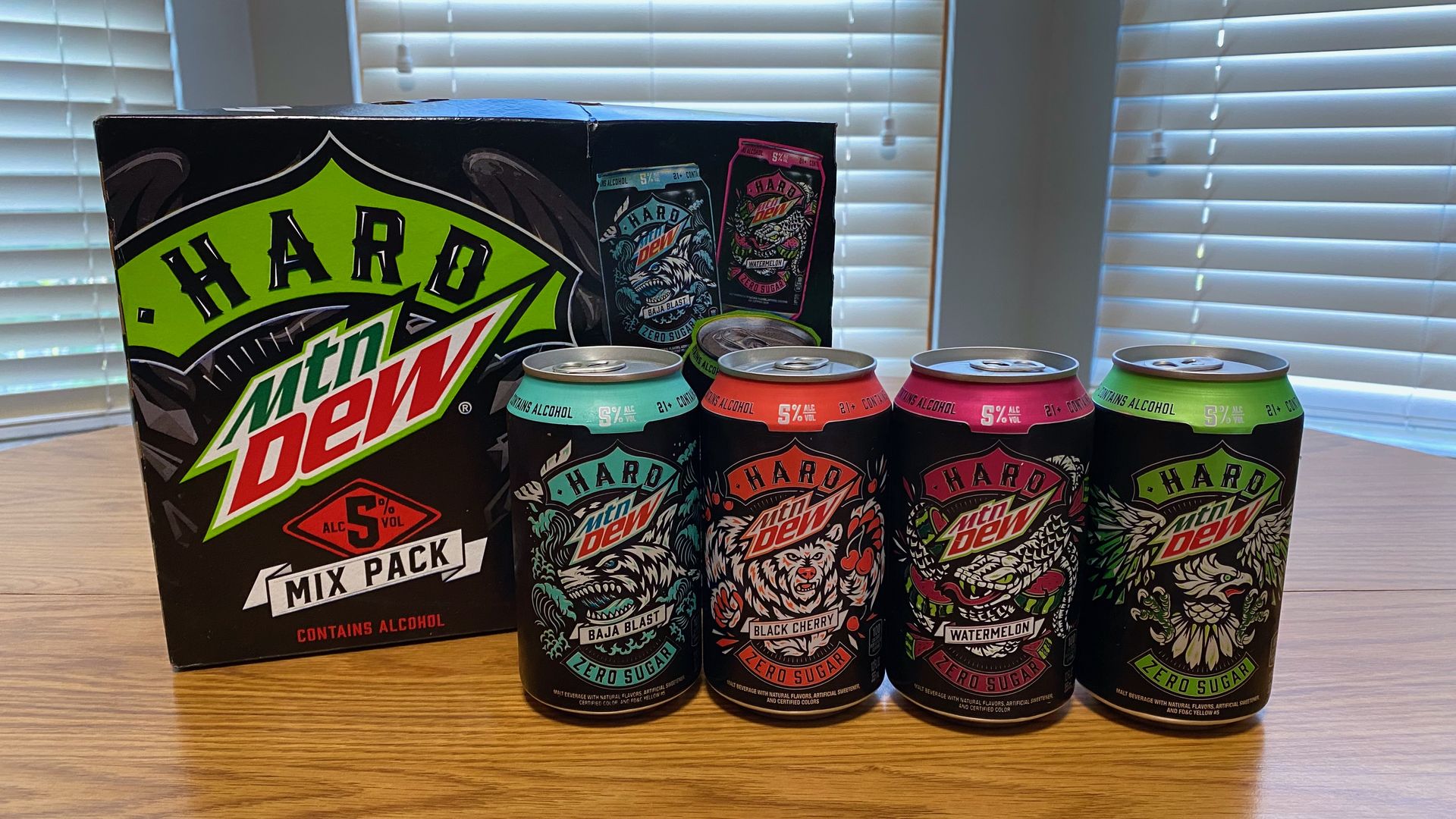 A Hard Mountain Dew mix pack box on a table, with four cans of different flavors lined in front of it
