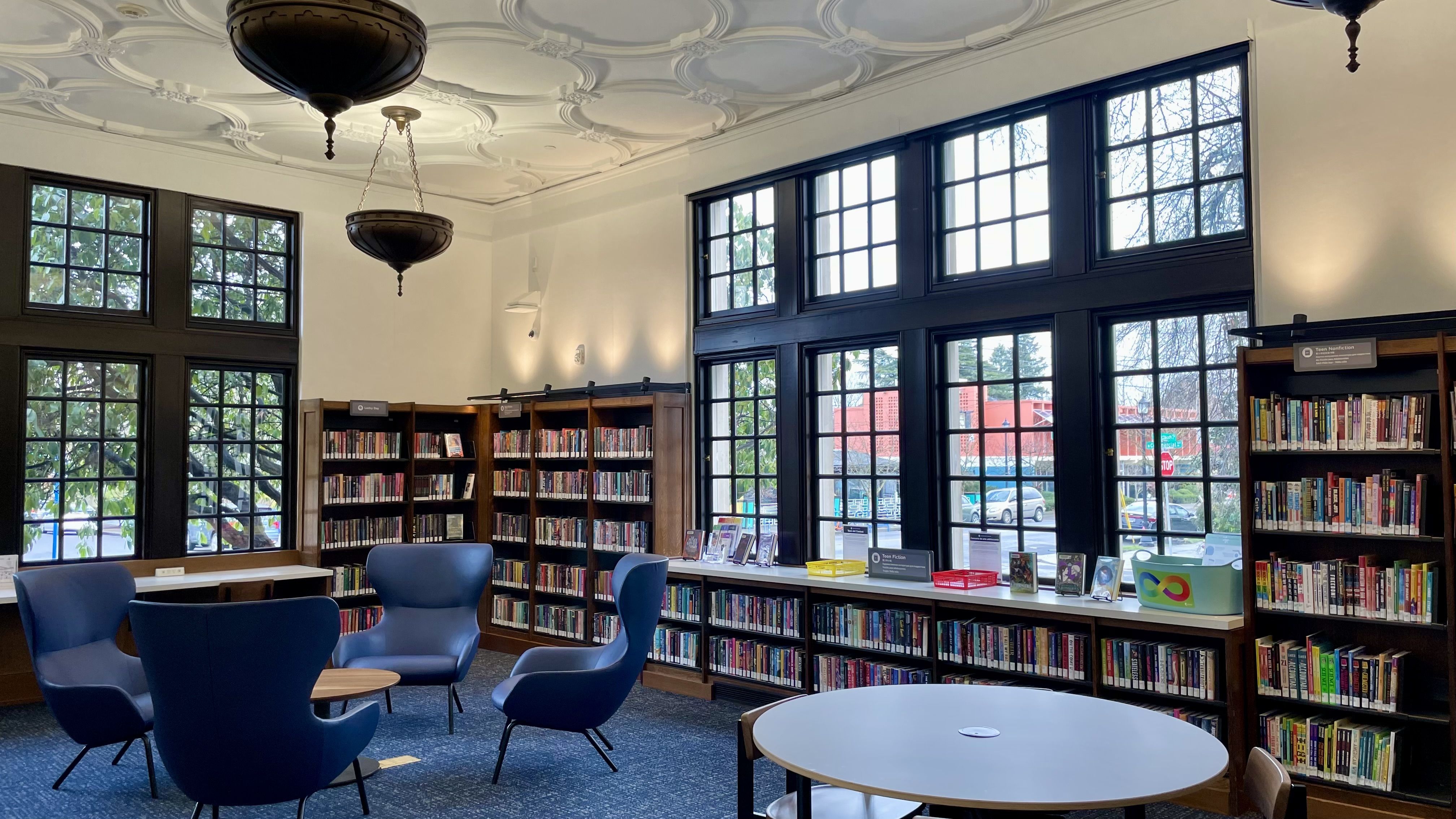 A photo of four blue chairs surrounding a round table in a library.