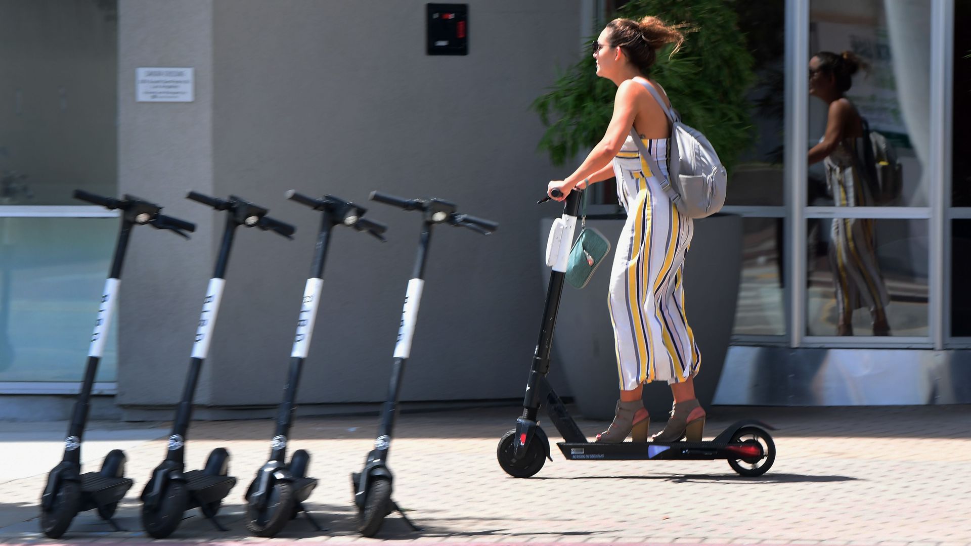 A woman riding an e-scooter in a city.