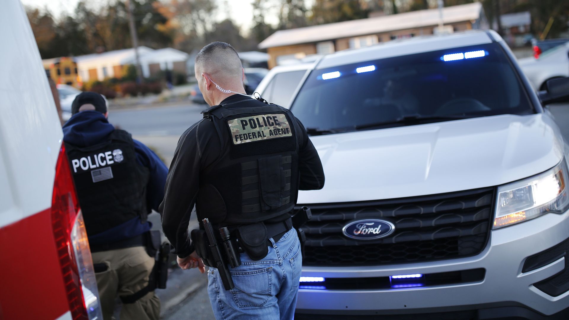 Photo of two federal agents walking around a vehicle at a traffic stop