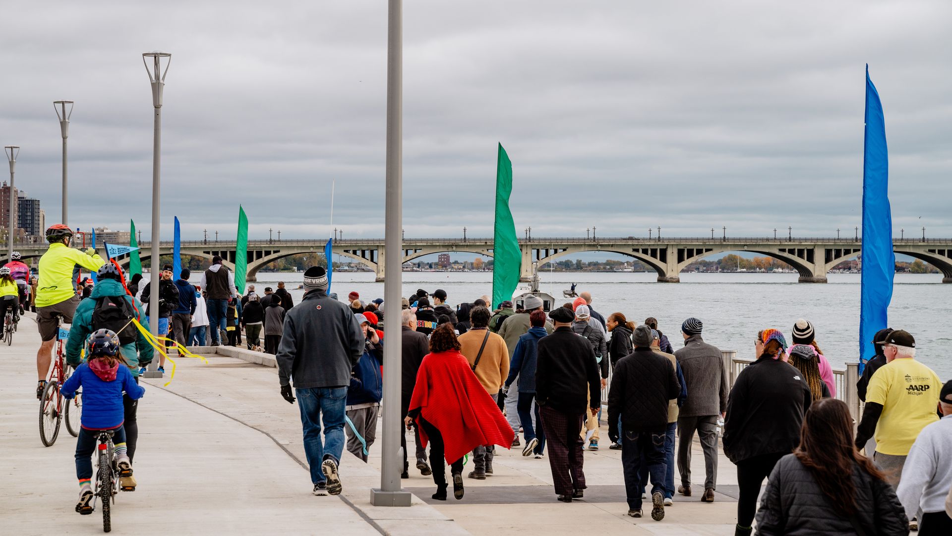 People walk along a concrete path with the river in the background.
