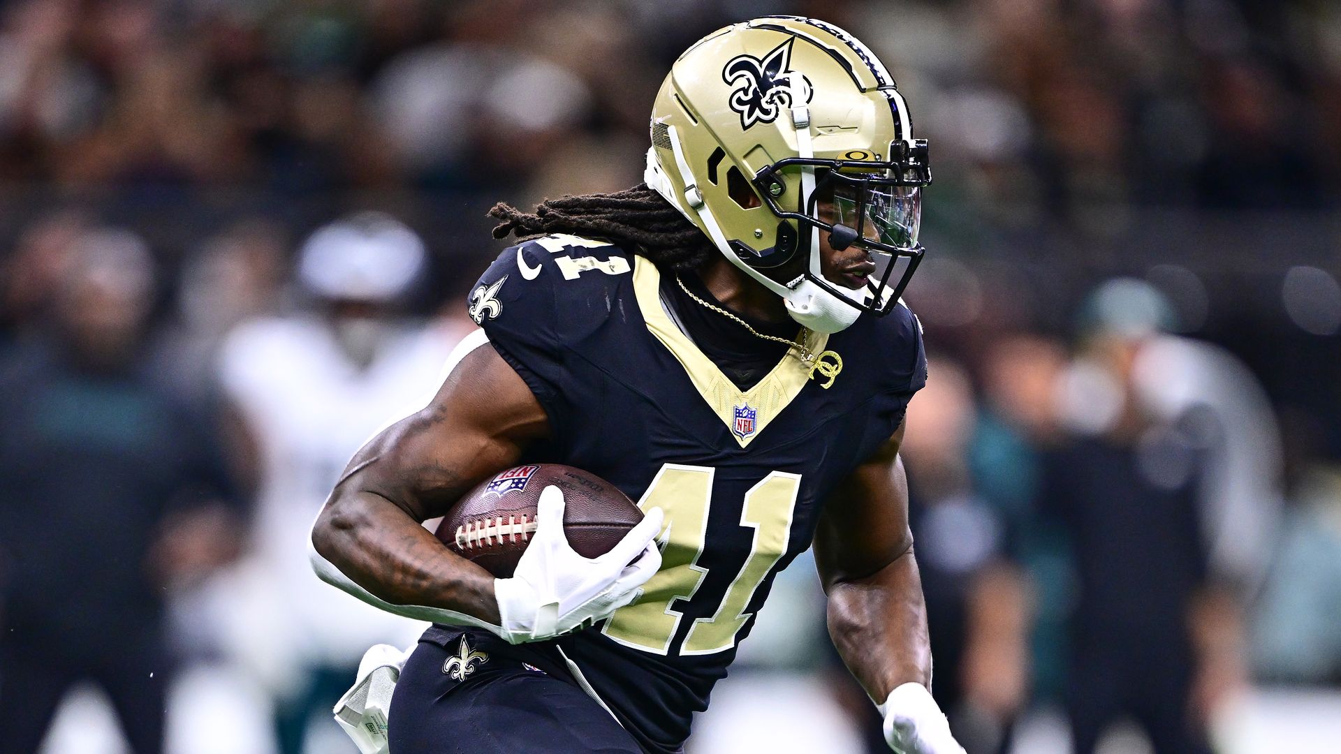 Image show Alvin Kamara running with a football.