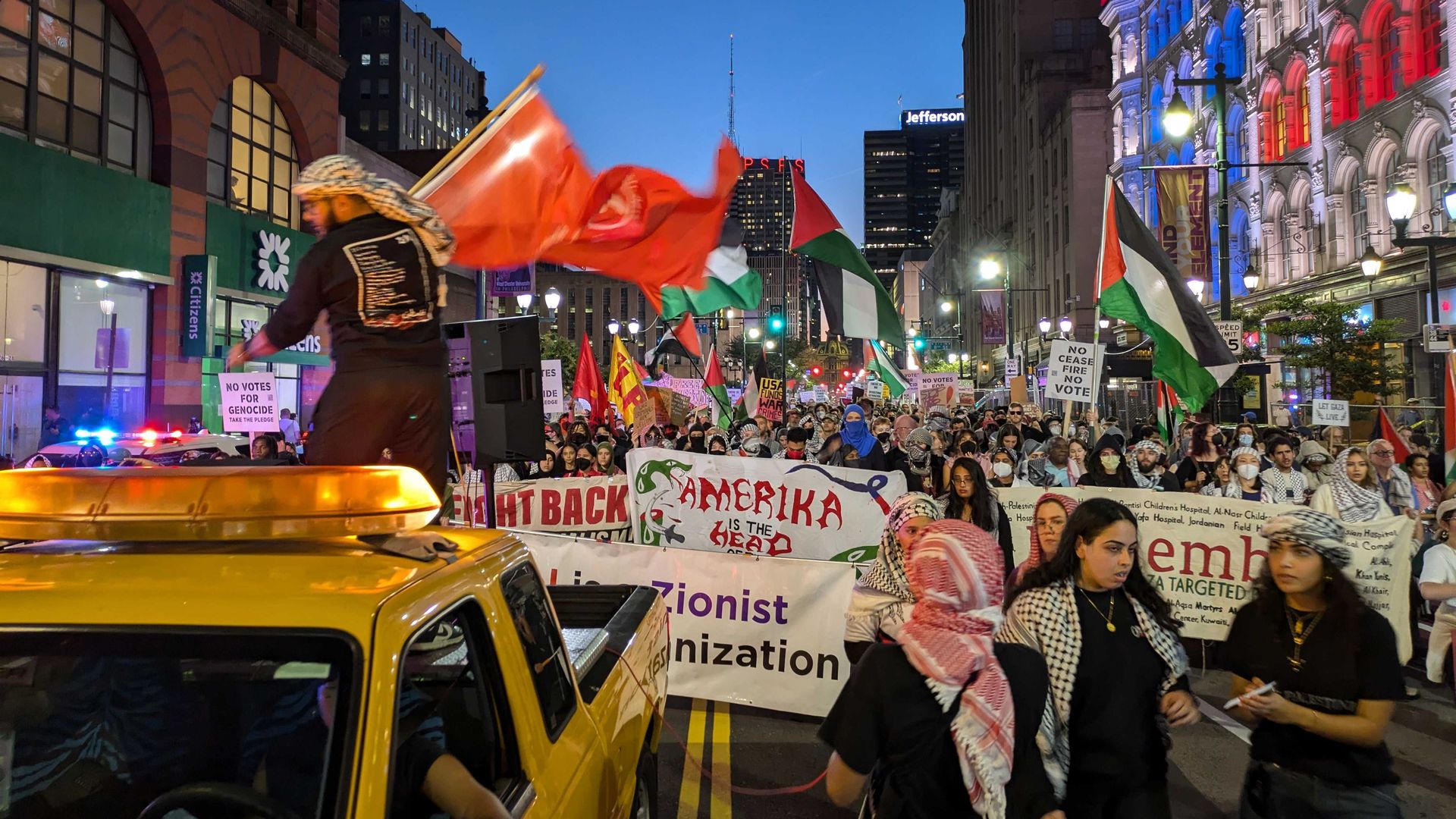 Pro-Palestinian protesters with signs and Palestinian flags fill Market Street.