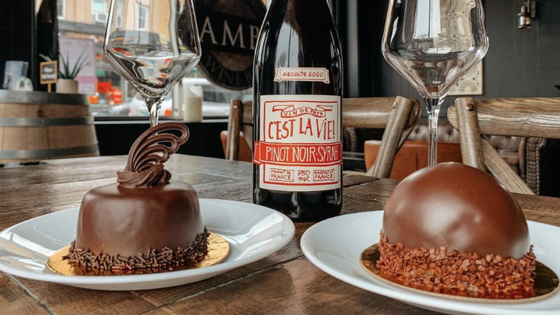 A photo of two chocolate tortes and a bottle of wine.