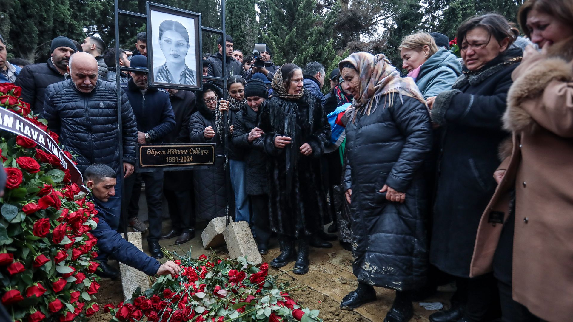 People mourn at the grave of flight attendant Hokuma Aliyeva, during the funeral of the crew members of Azerbaijan Airlines Flight J2-8243 that crashed near the Kazakh city of Aktau on December 29, 2024 in Baku, Azerbaijan. 