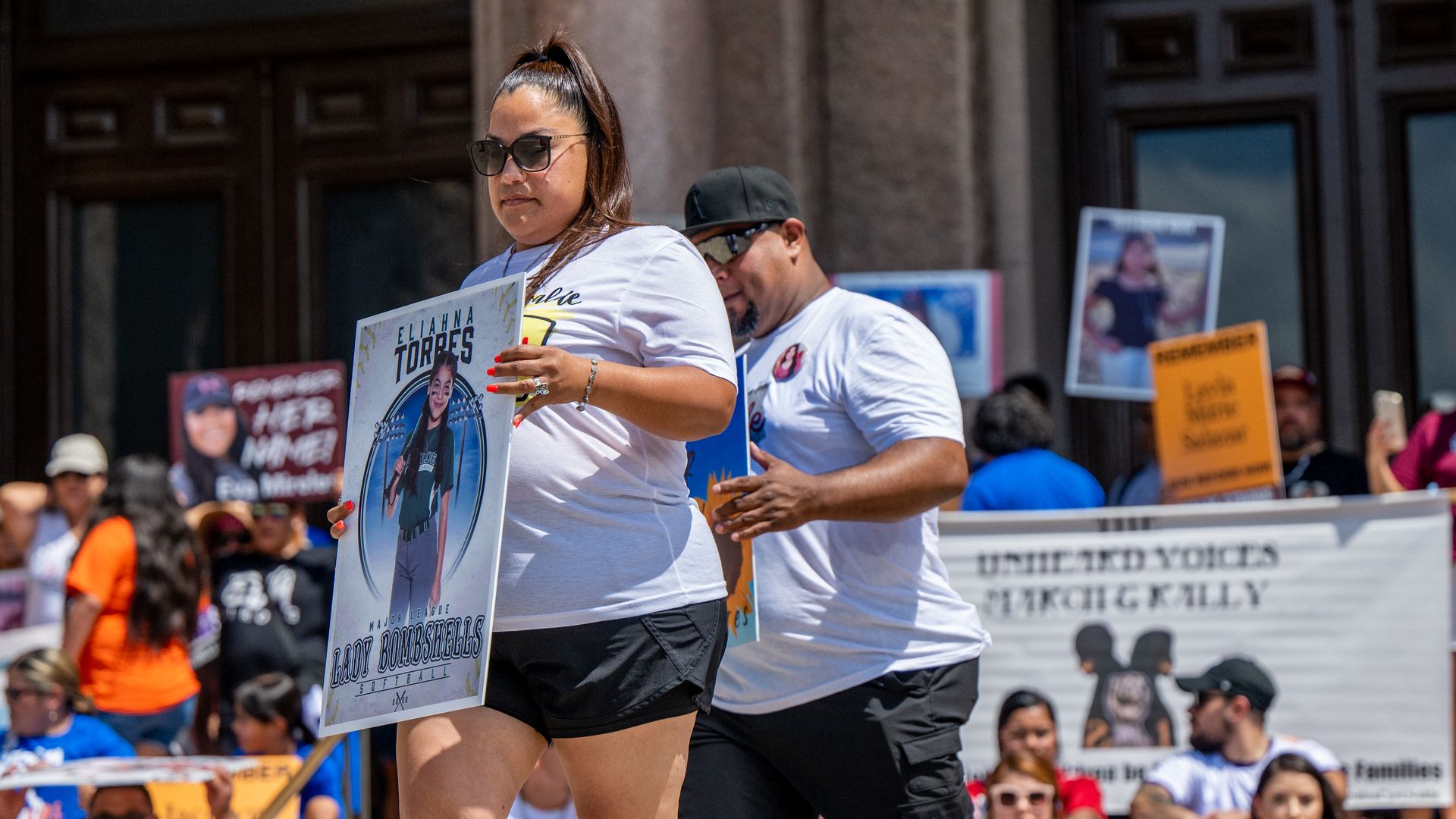 A woman holding a sign with a little girl's picture, an Uvalde victim, marches outside the Texas capitol