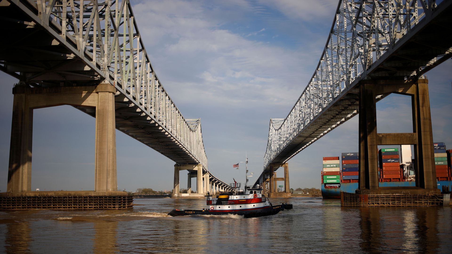 A tugboat passes beneath the twin spans of the Crescent City Connection.