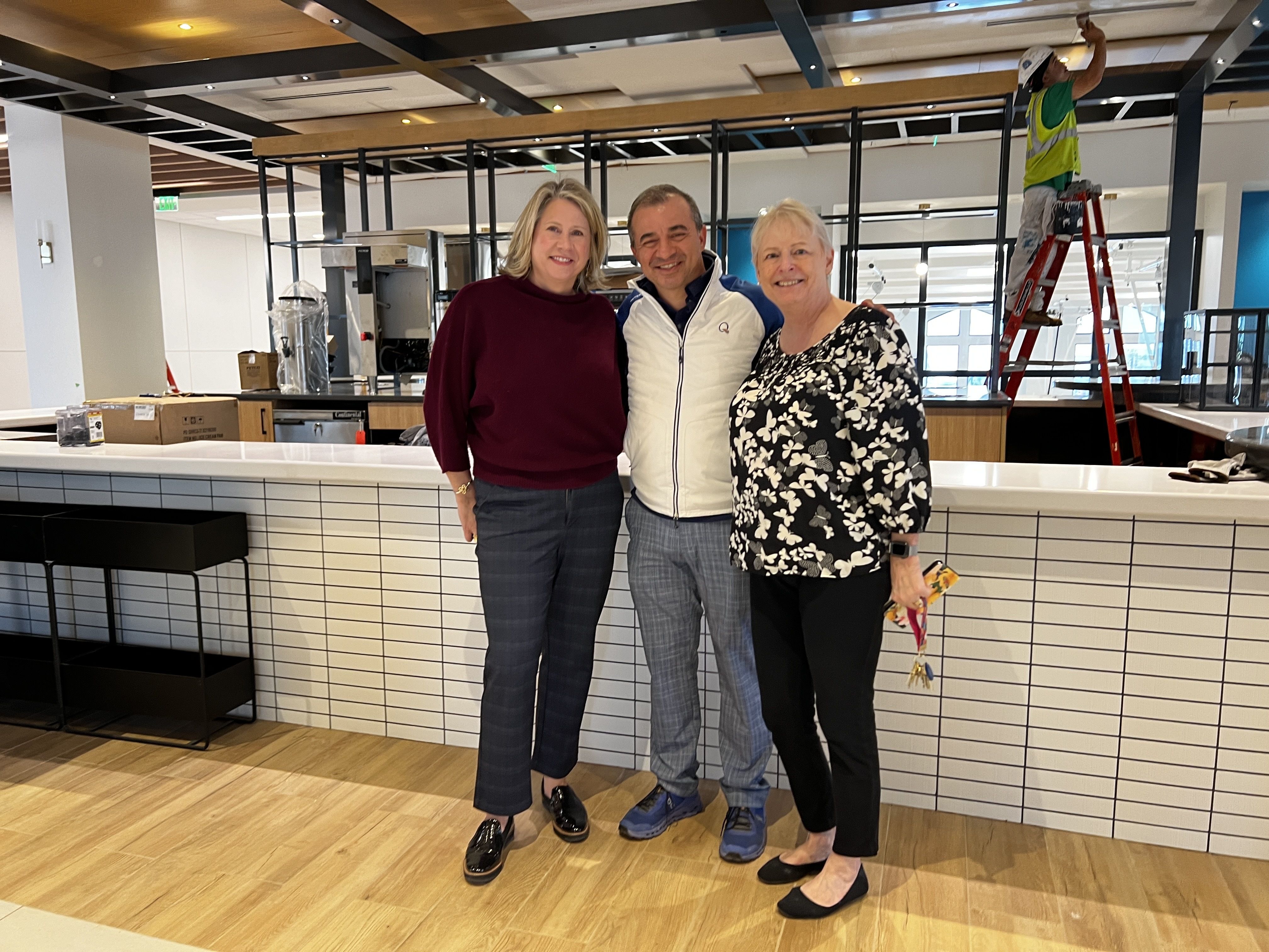 three people stand inside cafe that's under construction