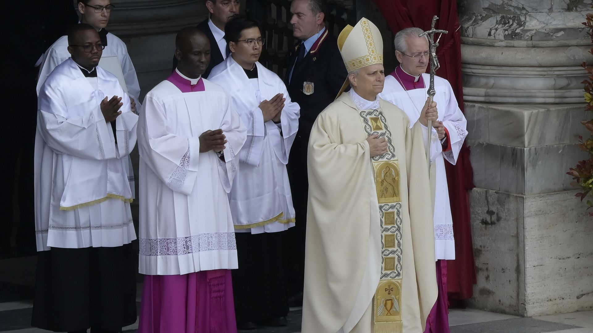 Photo of the pope outside surrounded by people in white robes. 
