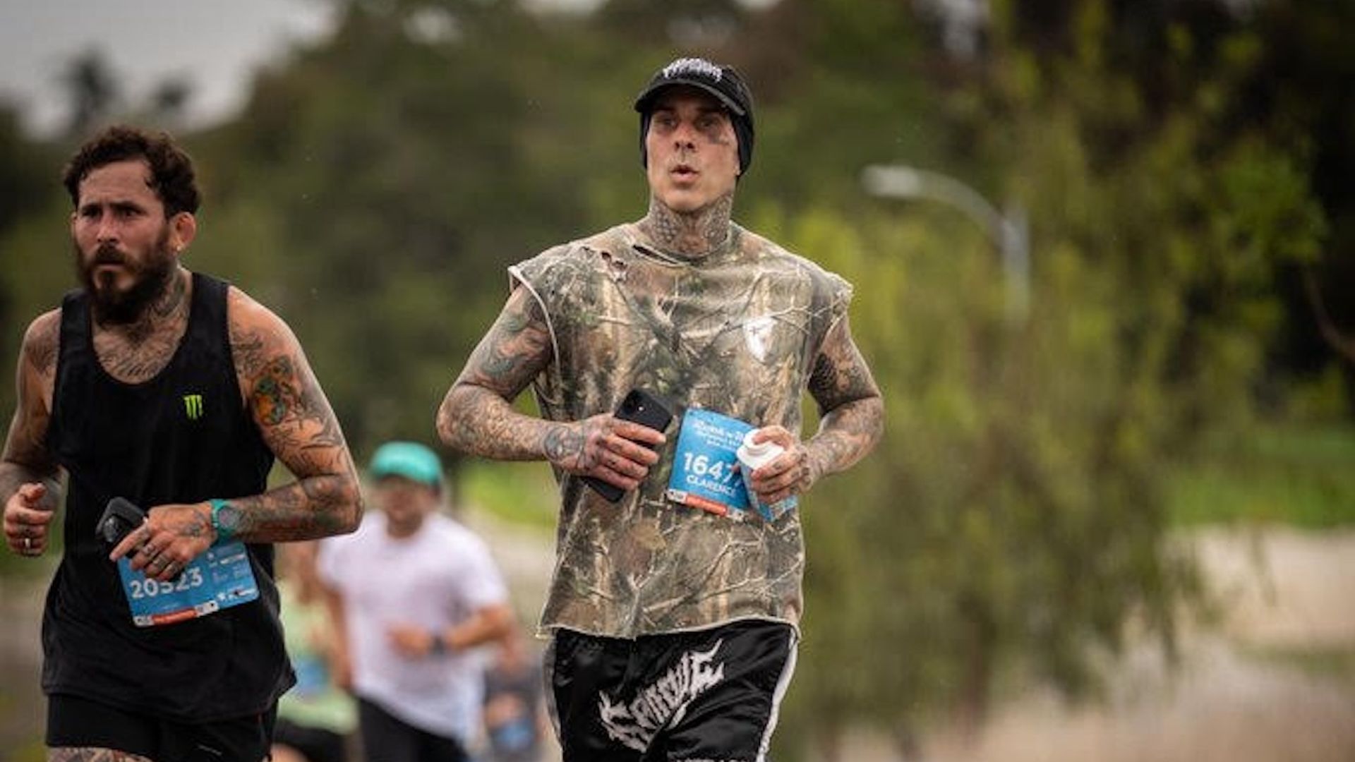 Travis Barker from Blink-182 runs in a camouflage hunting shirt