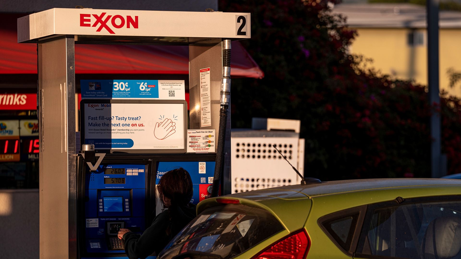 A woman fills up her car with gas at an Exxon gas station.