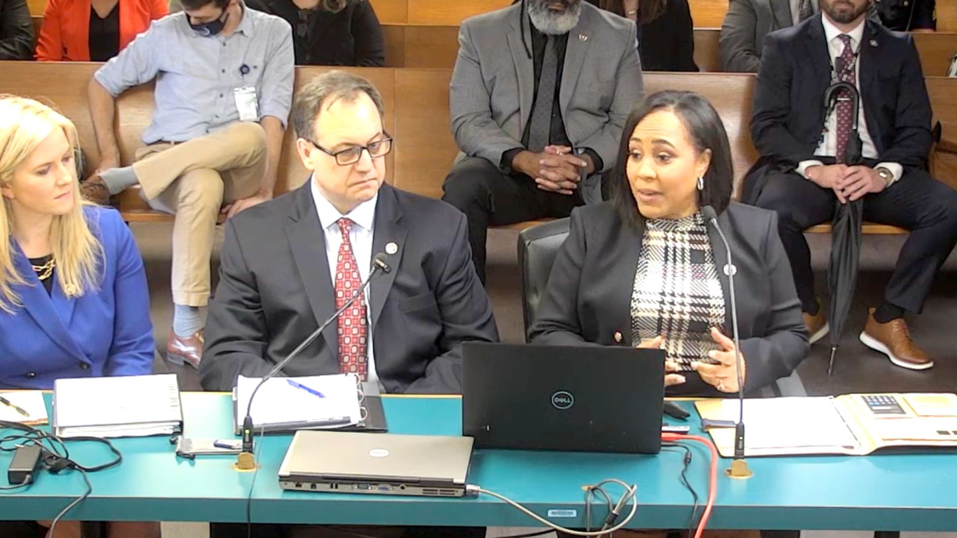 Fulton County District Attorney sits at a green table while addressing state lawmakers about COVID's effect on case backlogs