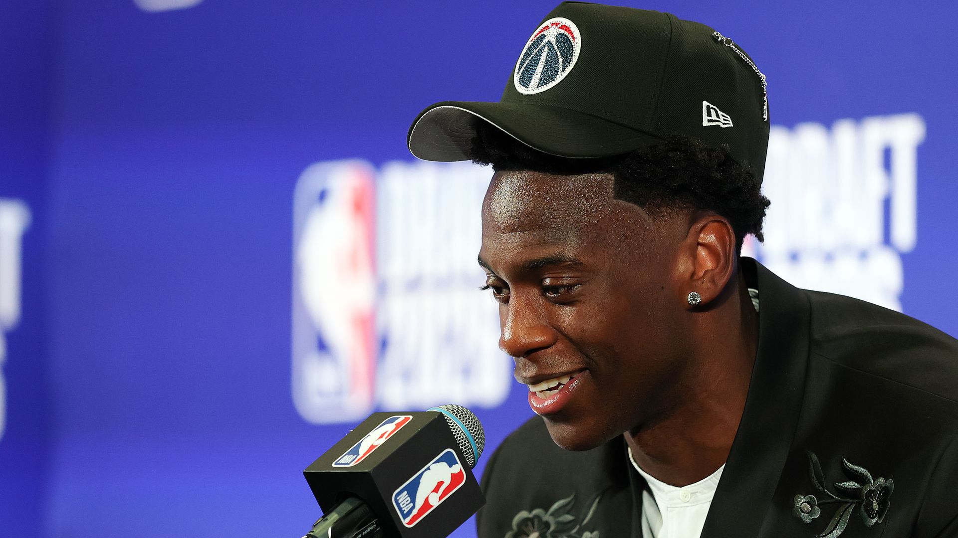 AJ Dybantsa, wearing a Wizards hat, speaks into a microphone on draft night