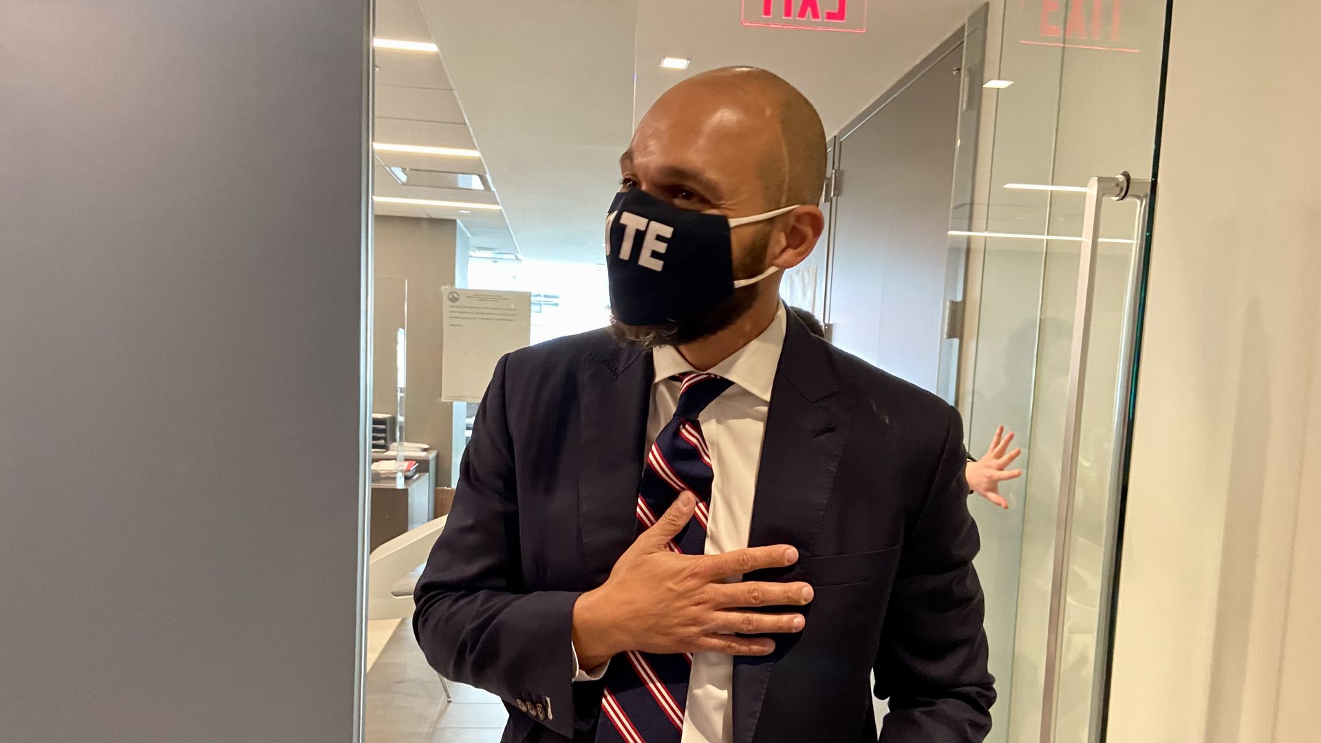 Robert White exits the Office of Campaign Finance after filing to run for mayor, wearing a "vote" face mask. 