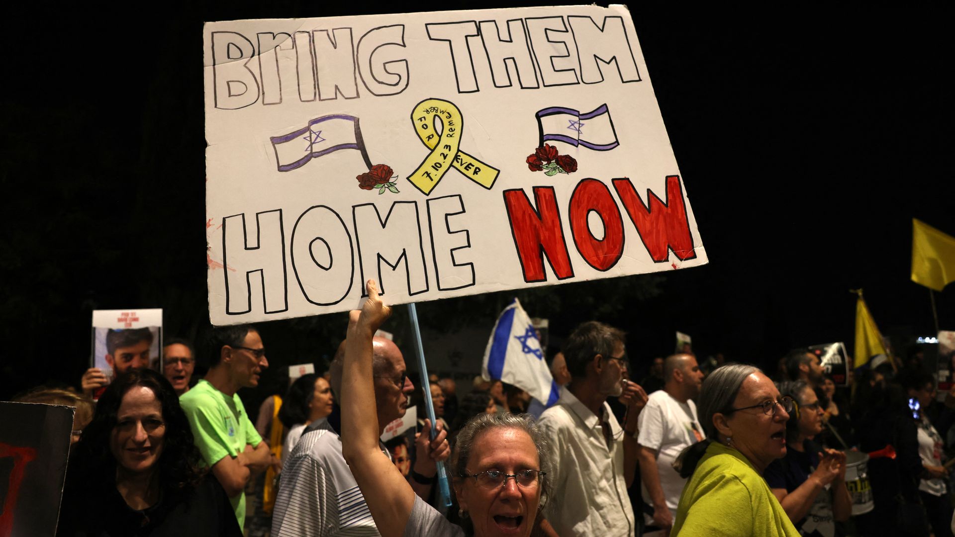 Relatives and supporters raise placards bearing messages and portraits of Israeli hostages