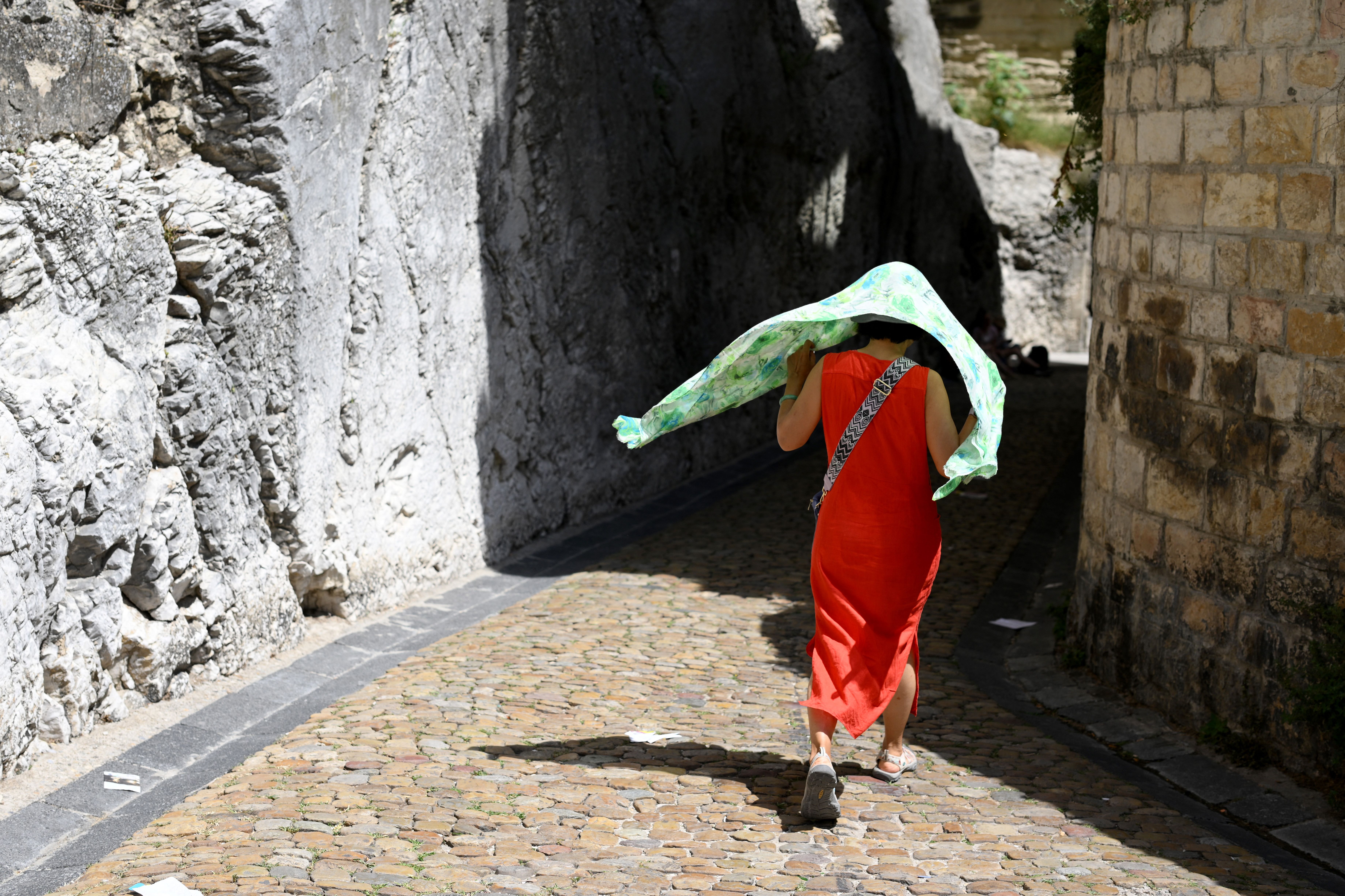 A woman covers herself with a scarf in Avignon, southern France, on July 17, 2023. 