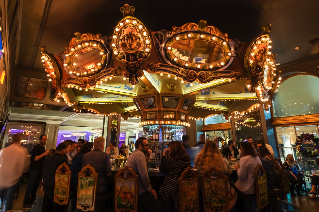 Photo shows the carousel inside the Carousel Bar surrounded by people.