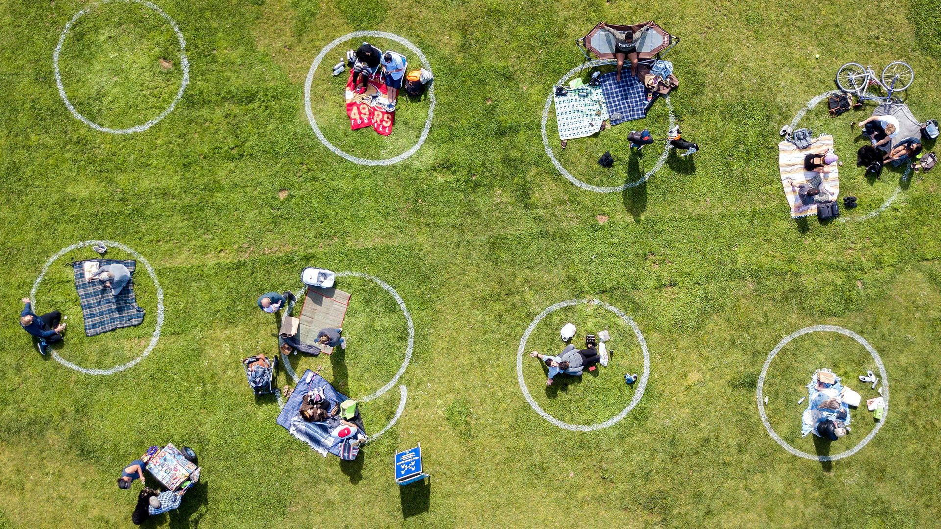 In this image, people sit in separate chalk circles on a grassy field