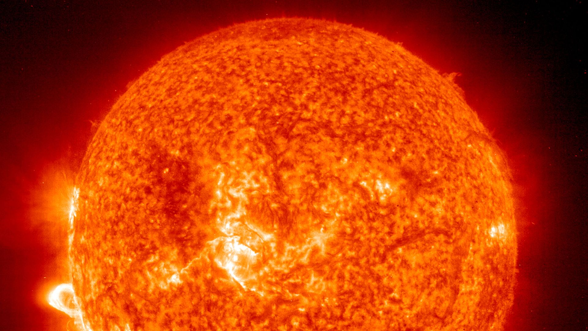 This image shows the sun from a distance, with flare-ups on its lower left side.